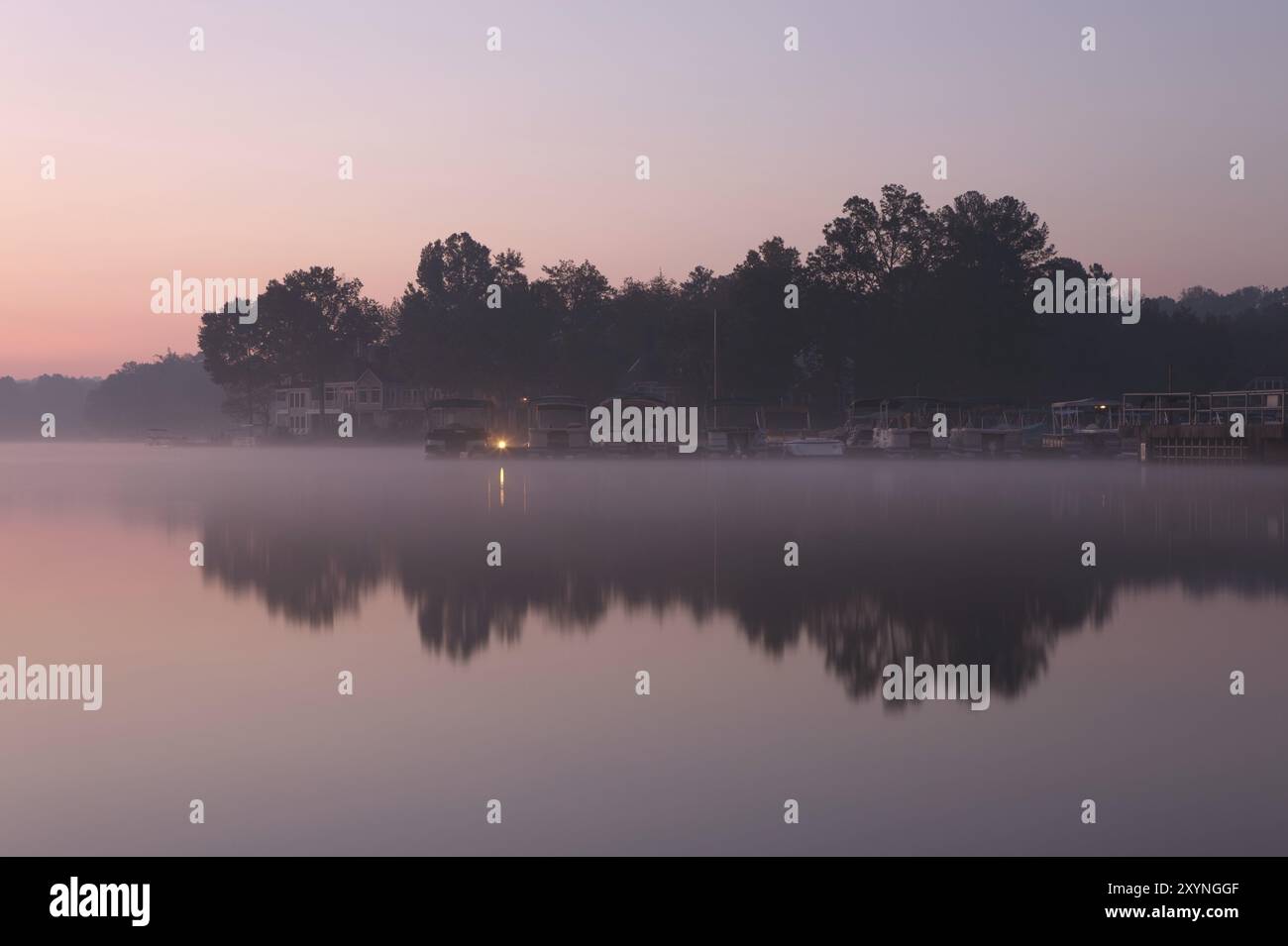 Misty morning at the lake with houses and jetty Stock Photo - Alamy