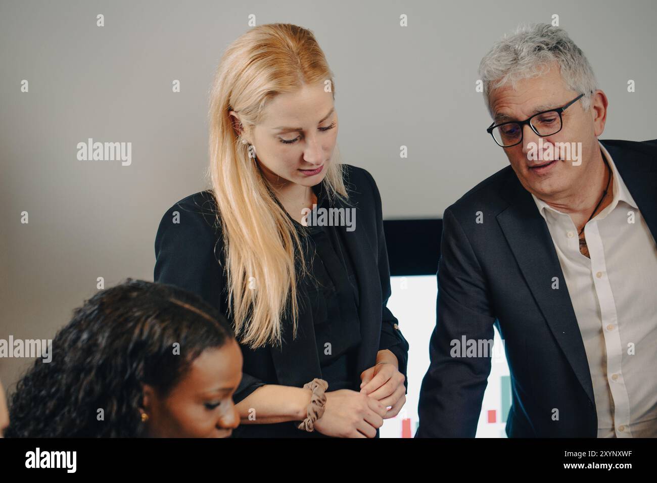 Business team having a discussion while analyzing data on a digital screen Stock Photo
