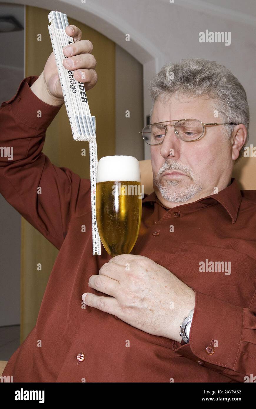 Man checks the level of the beer glass with a folding rule Stock Photo