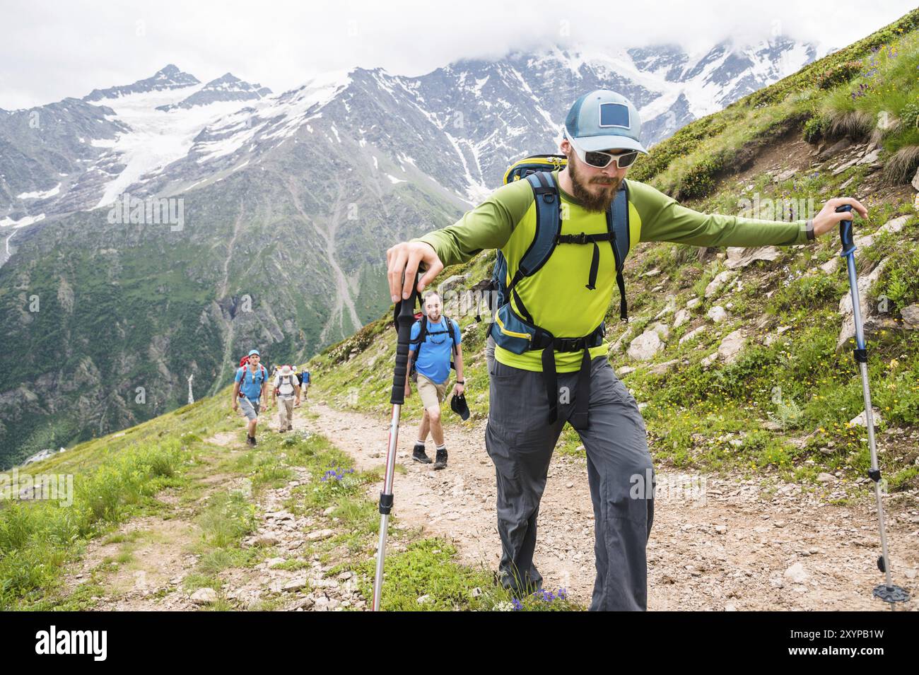 Portrait of a group of tourists with backpacks climbing a mountain ...