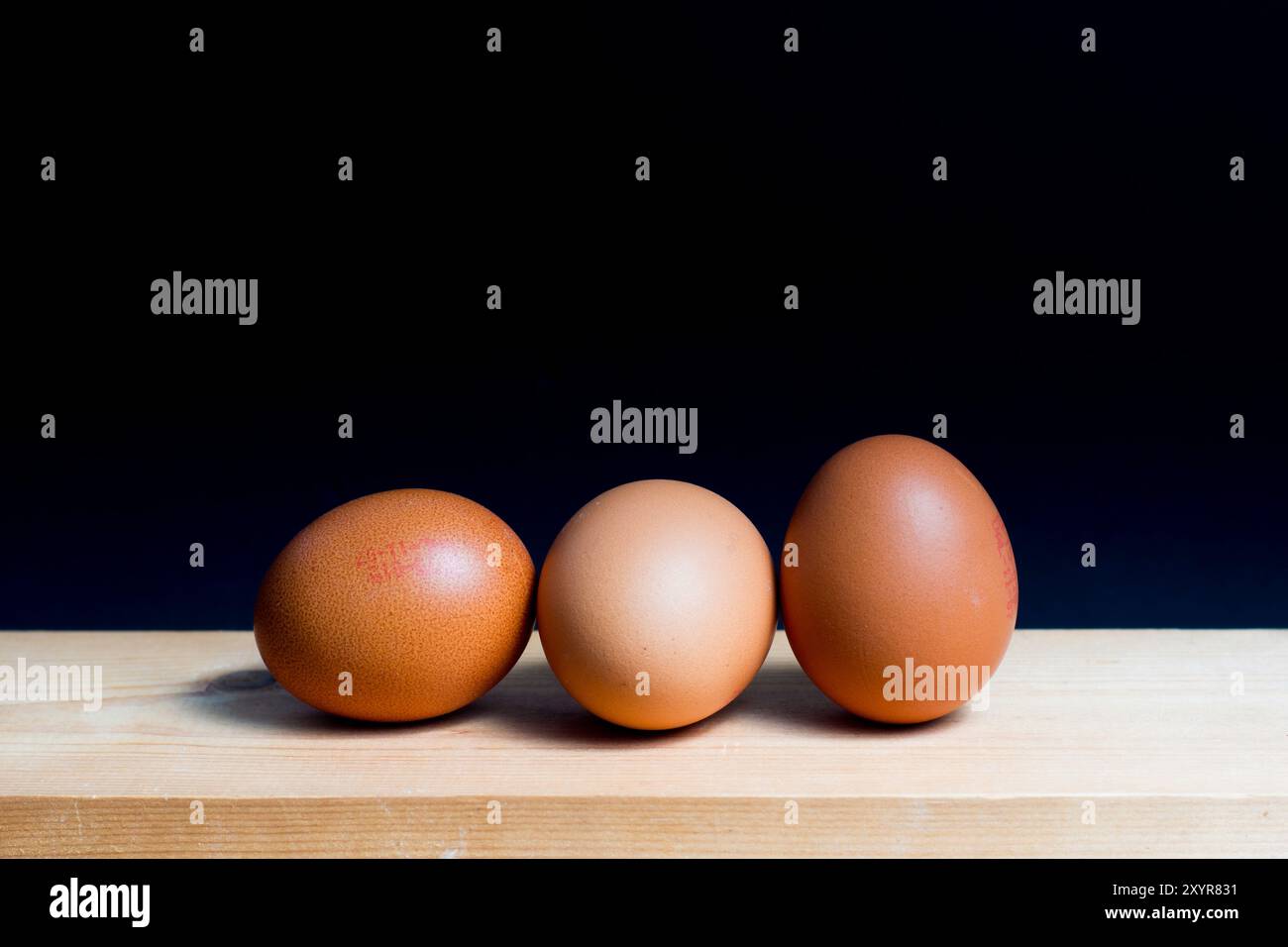 three eggs disposed on table against black background Stock Photo