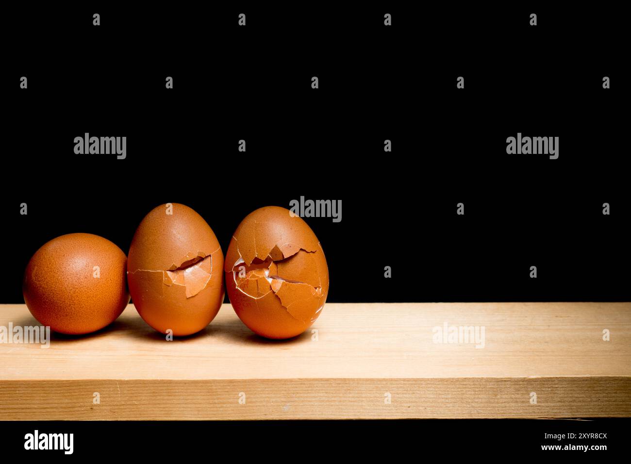 next egg to break - three eggs on table against black background Stock Photo