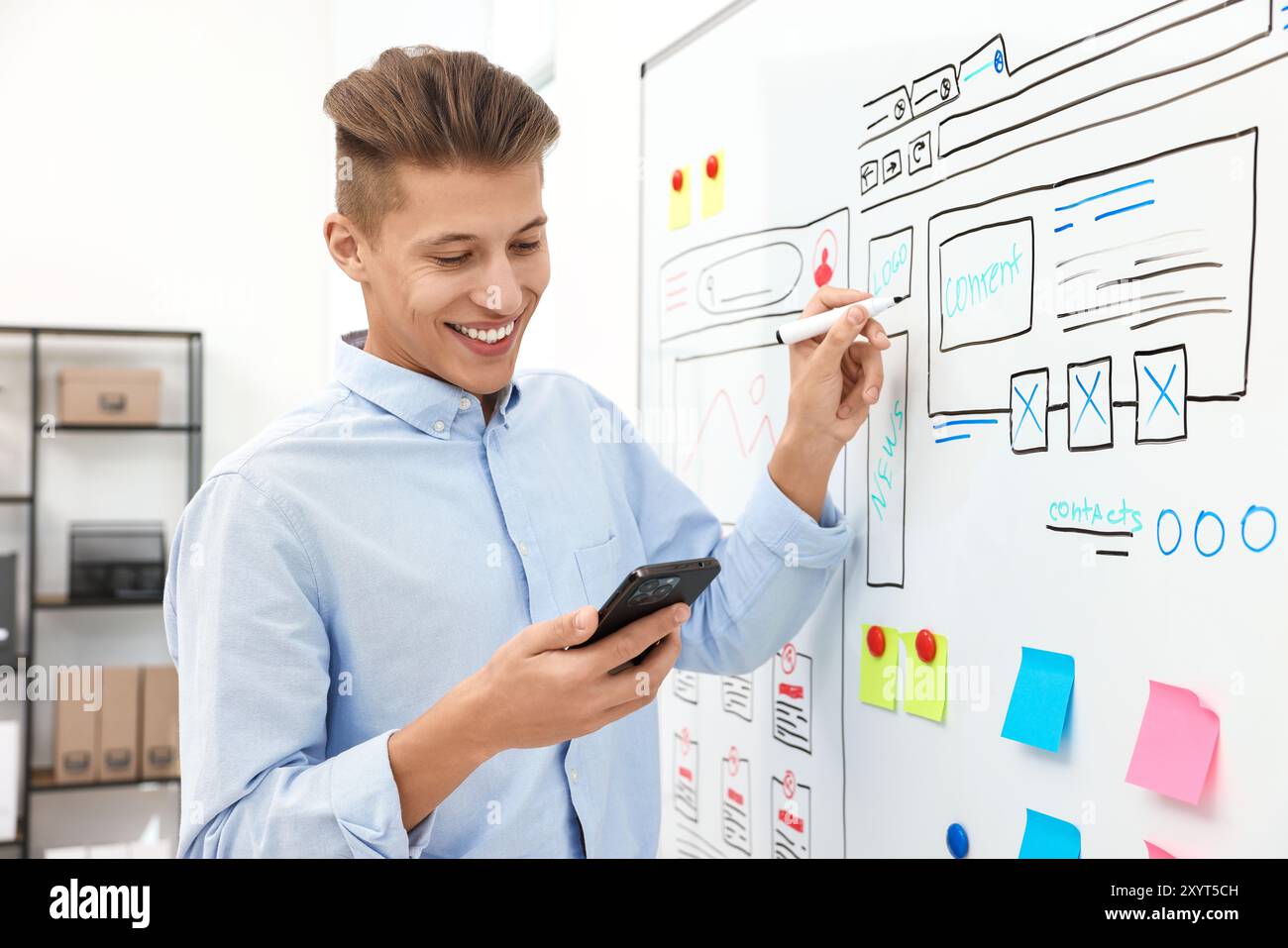 Developing UI design. Man drawing website wireframe on whiteboard indoors Stock Photo