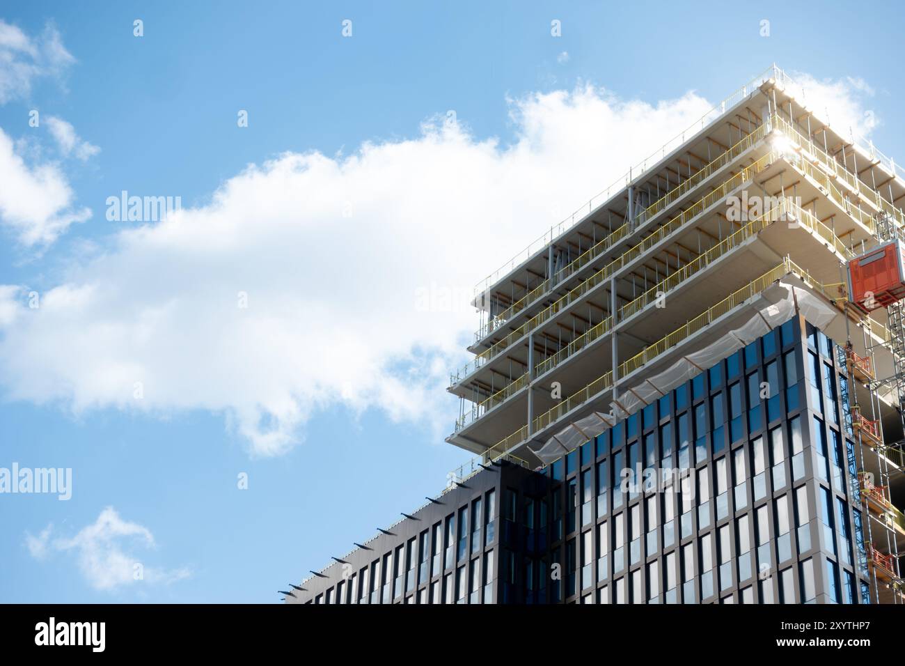 Construction site of modern glass facade skyscraper building with a crane against clear sky background, constructing Sickla Central office building Stock Photo