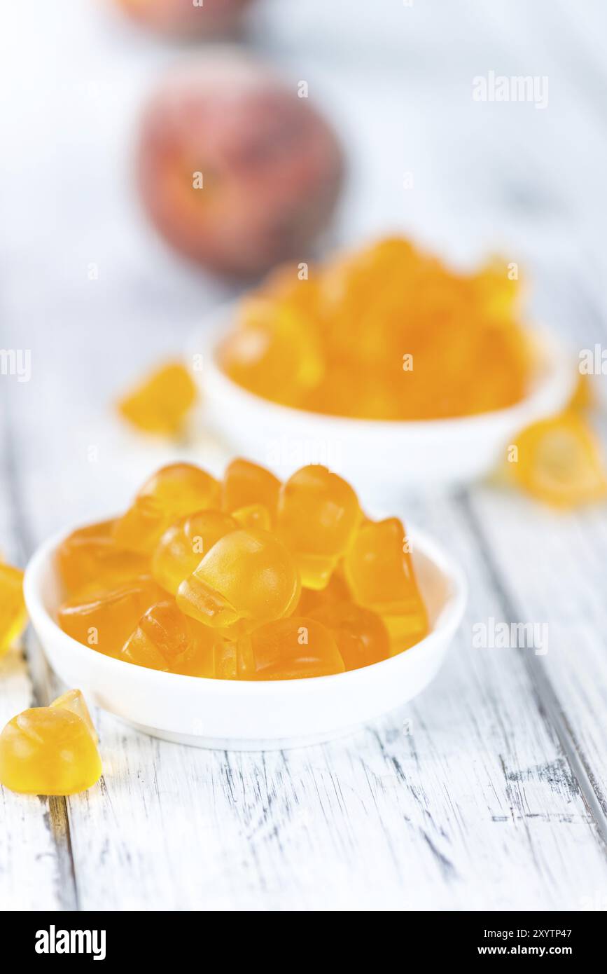 Heap of gummy Peaches on wooden background (close-up shot) Stock Photo