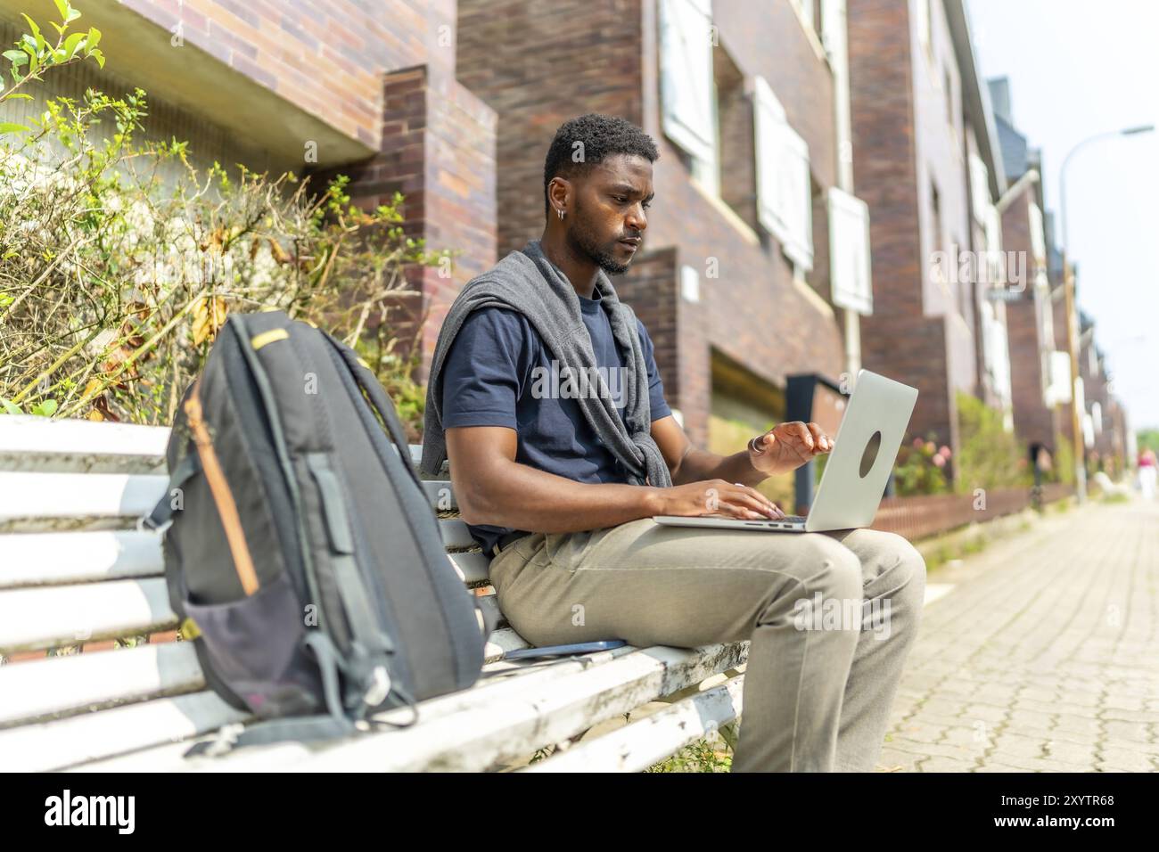 Side view portrait of a young african man working with laptop sitting ...