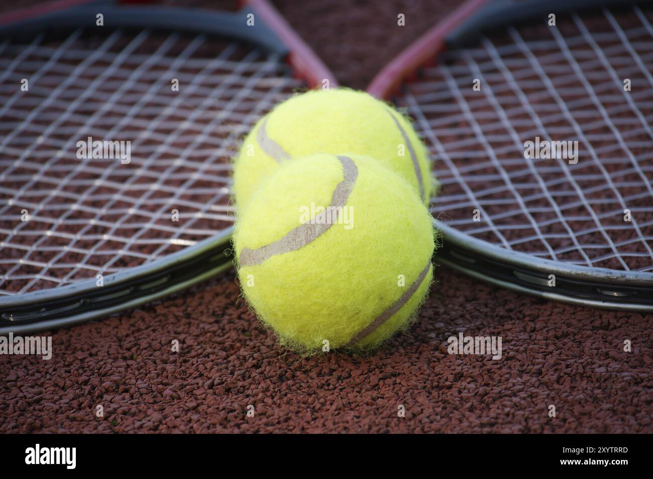 Two yellow tennis balls and two racquets on hard tennis court surface ...