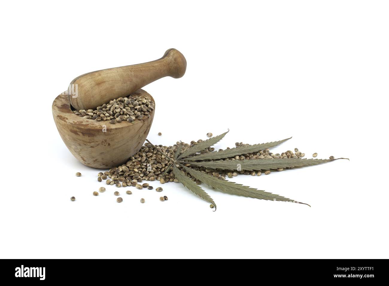 Hemp seeds in wooden rustic-style mortar near pestle and cannabis plant leaf isolated on white background Stock Photo