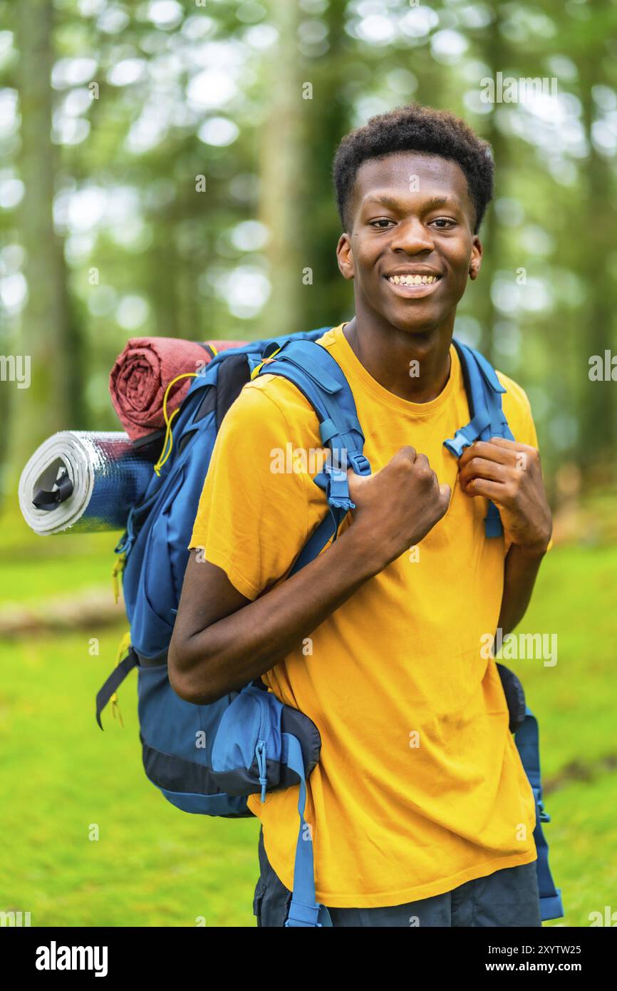 Vertical portrait of a young african man having a walk with a backpack ...