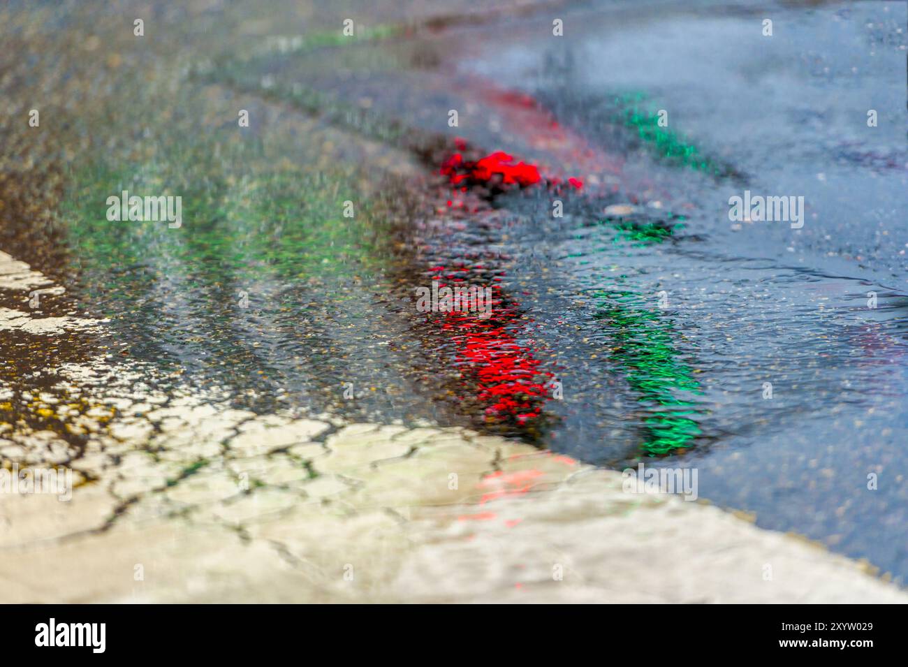 Reflection of traffic lights on the wet road surface of an intersection ...