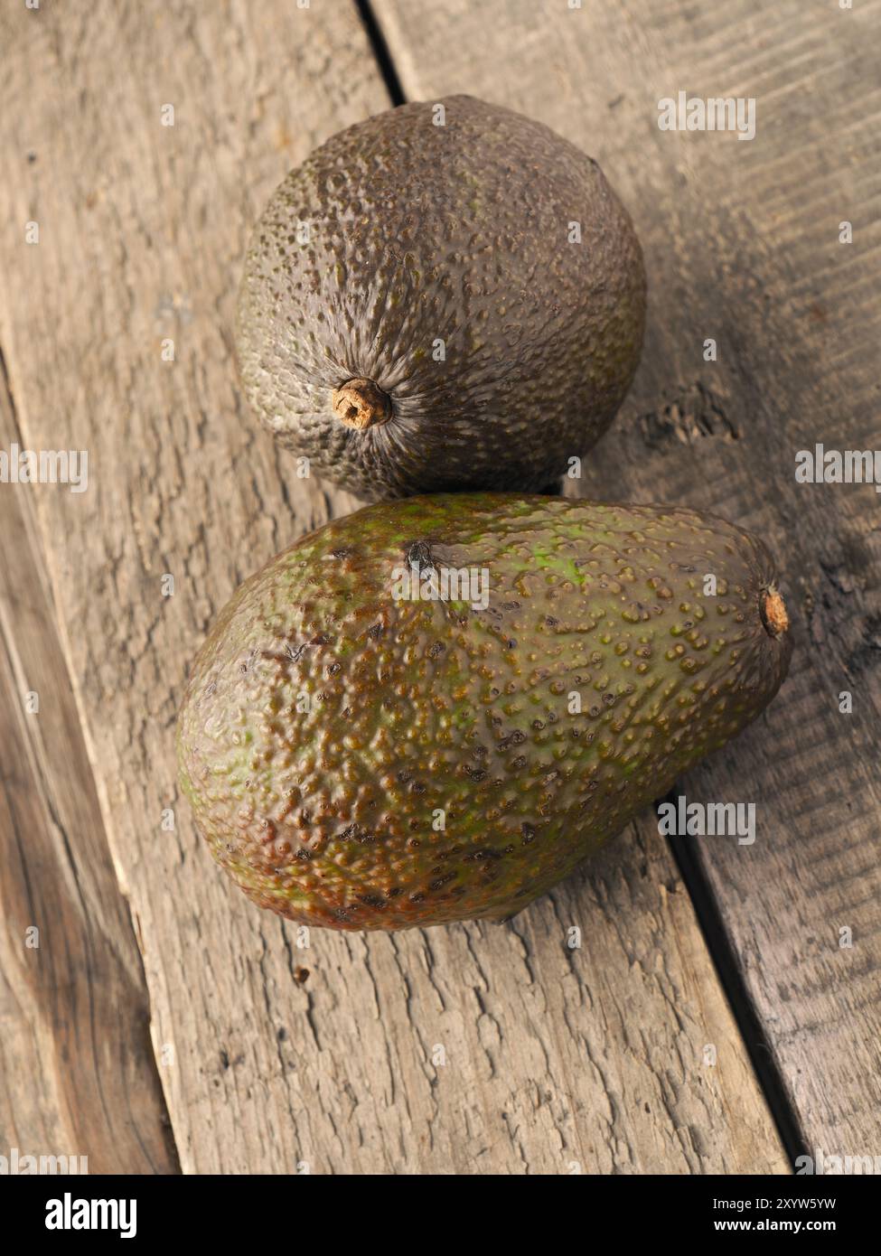 Two avocados on a rustic wooden kitchen table Stock Photo