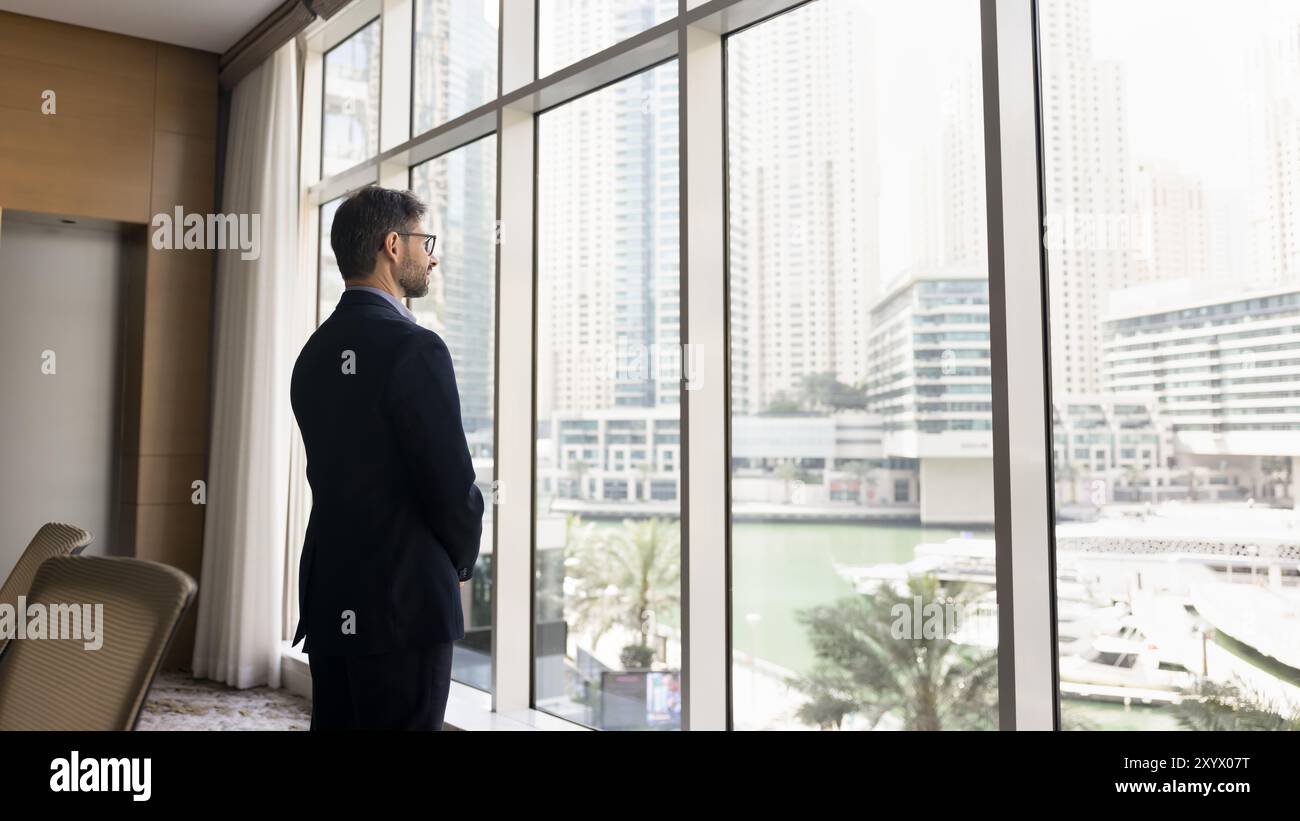 Serious confident business owner man in suit standing at window Stock Photo