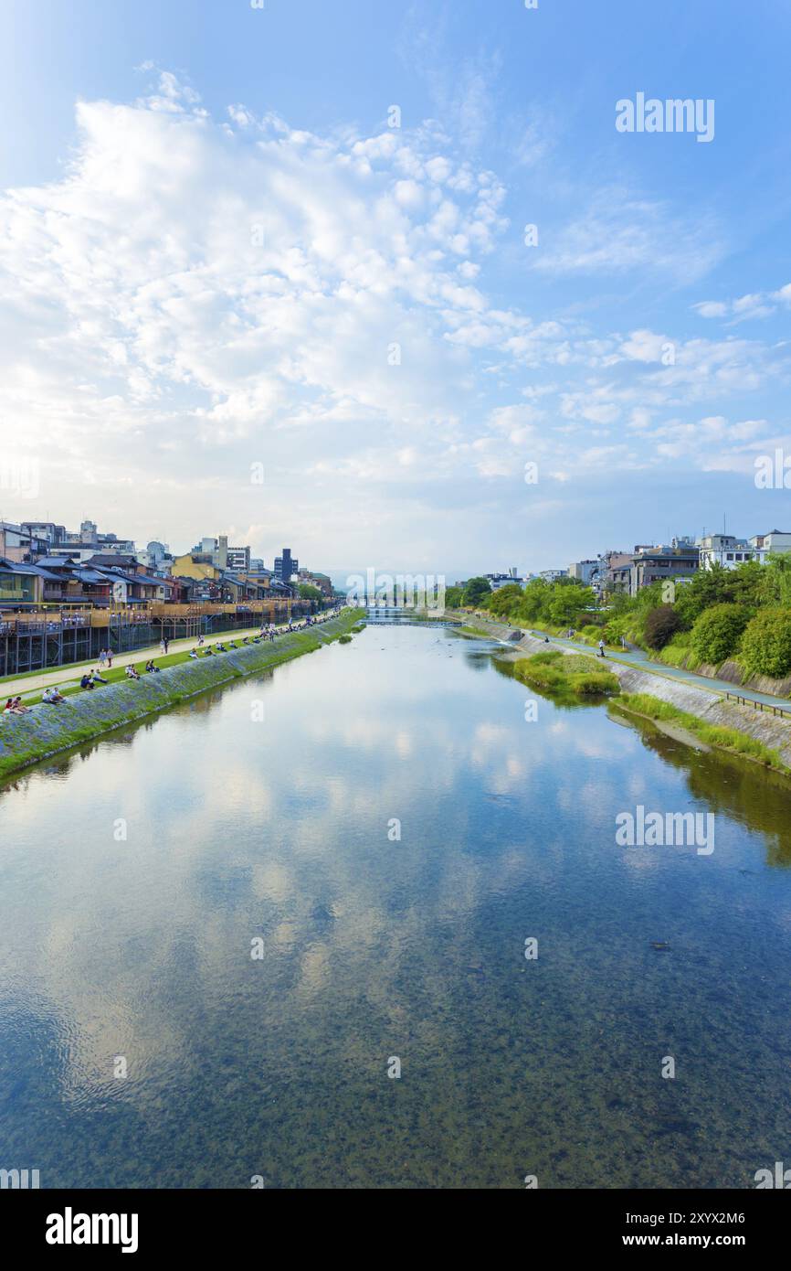 KYOTO, JAPAN, JUNE 20, 2015: People leisurely resting and restaurants line the banks of the Kamo River on a late afternoon on a blue sky day in centra Stock Photo