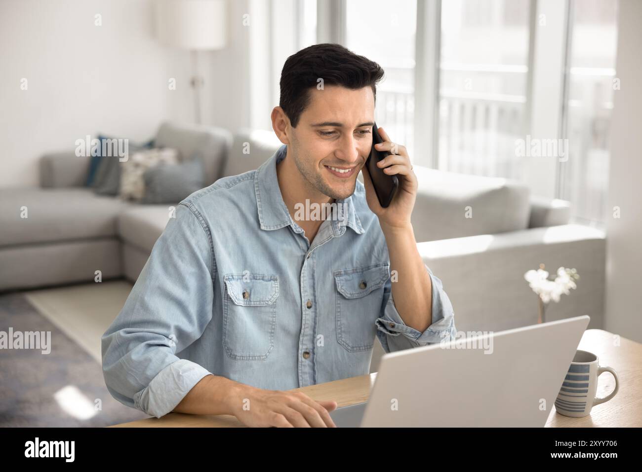 Positive young Hispanic freelance manager man talking on cellphone Stock Photo