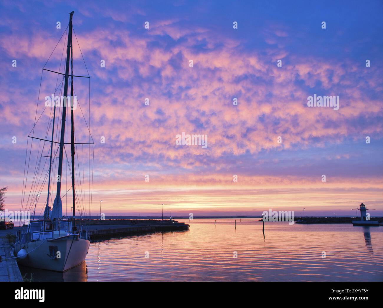 Sailing ship in the harbor of lake Vaettern at sunset. Lighthouse in ...