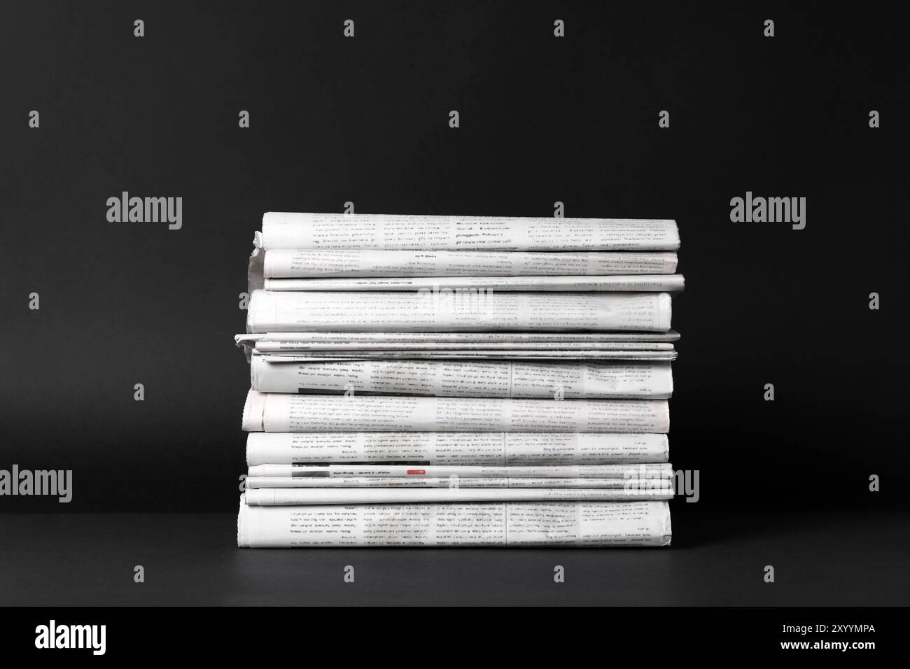 Stack of newspapers in different languages on black background Stock Photo
