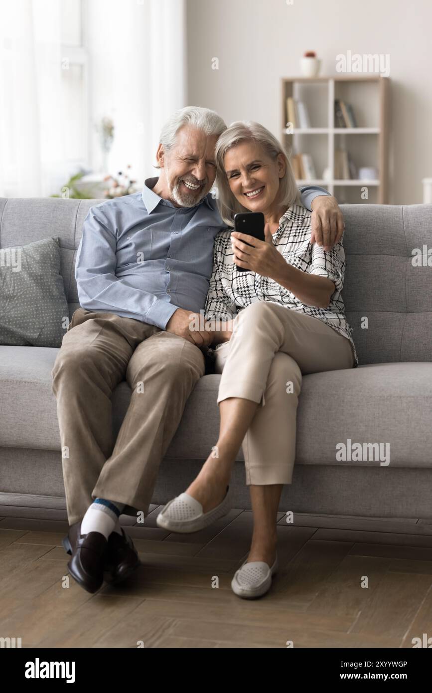 Attractive mature spouses spend pleasant time on internet using smartphone Stock Photo