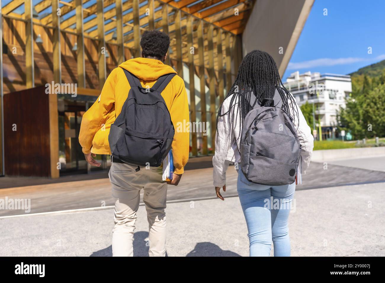 Rear view of two african students walking to the university together ...