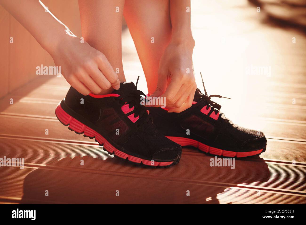 Unrecognizable female tying shoelaces on modern sneakers while preparing for training at home Stock Photo