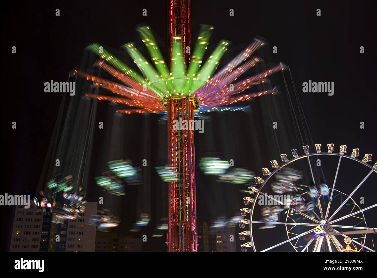 Carousel and ferris wheel in an amusement park at night Stock Photo