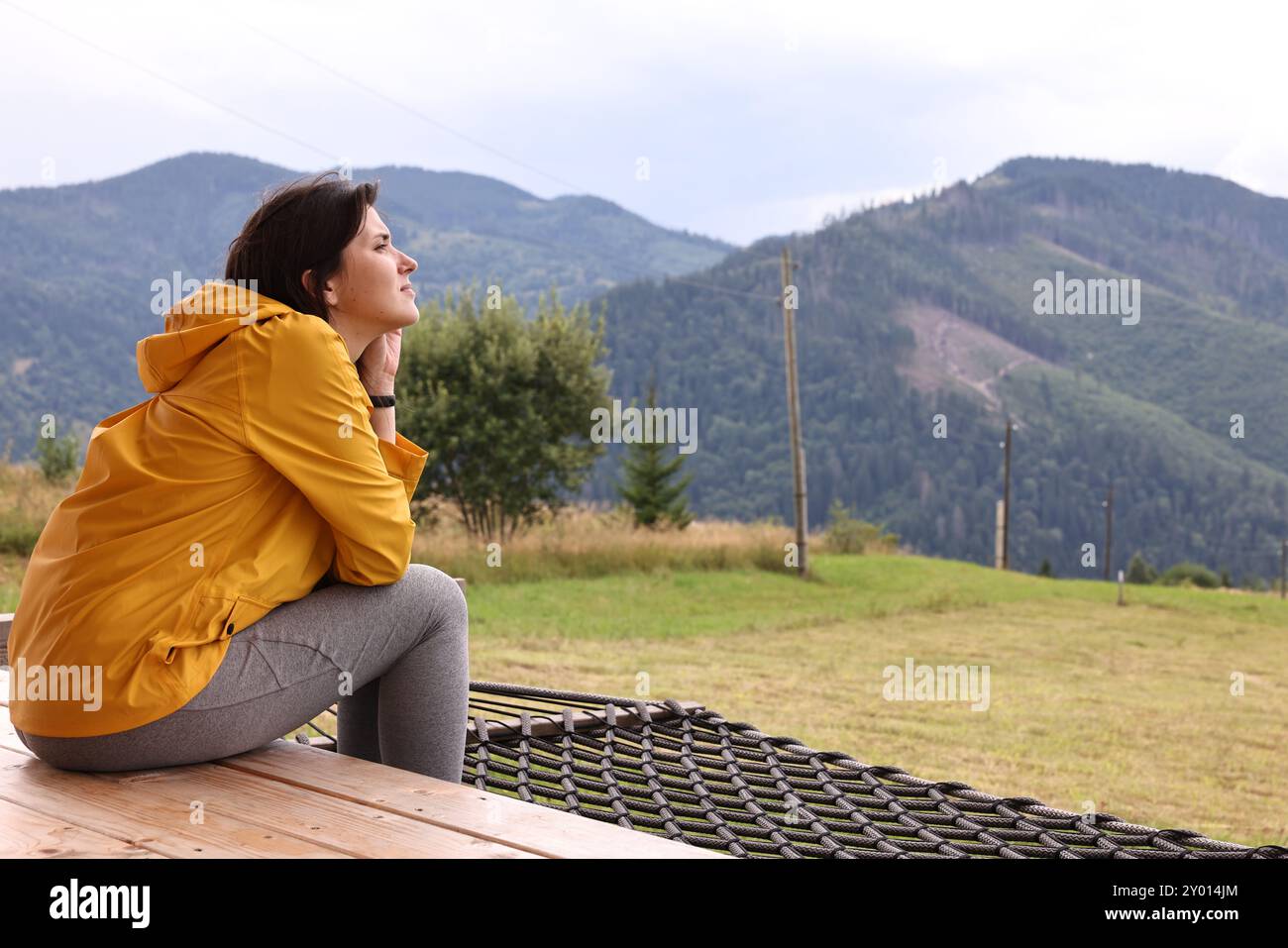 Young woman sitting on porch in mountains, space for text. Active tourism Stock Photo