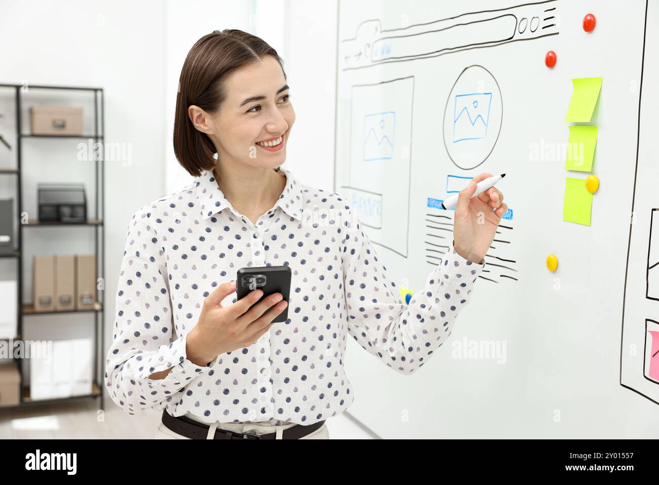 Developing UI design. Woman drawing website wireframe on whiteboard indoors Stock Photo