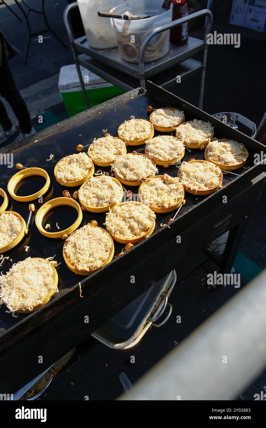 A view of a griddle cooking up several ramen noodle patties, using silicon ring molds to hold the noodles into shape. Stock Photo