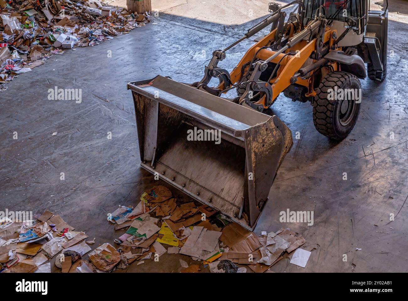 Orange excavator working recycled waste in recycle factory in Switrzerland. Recycling paper. Stock Photo