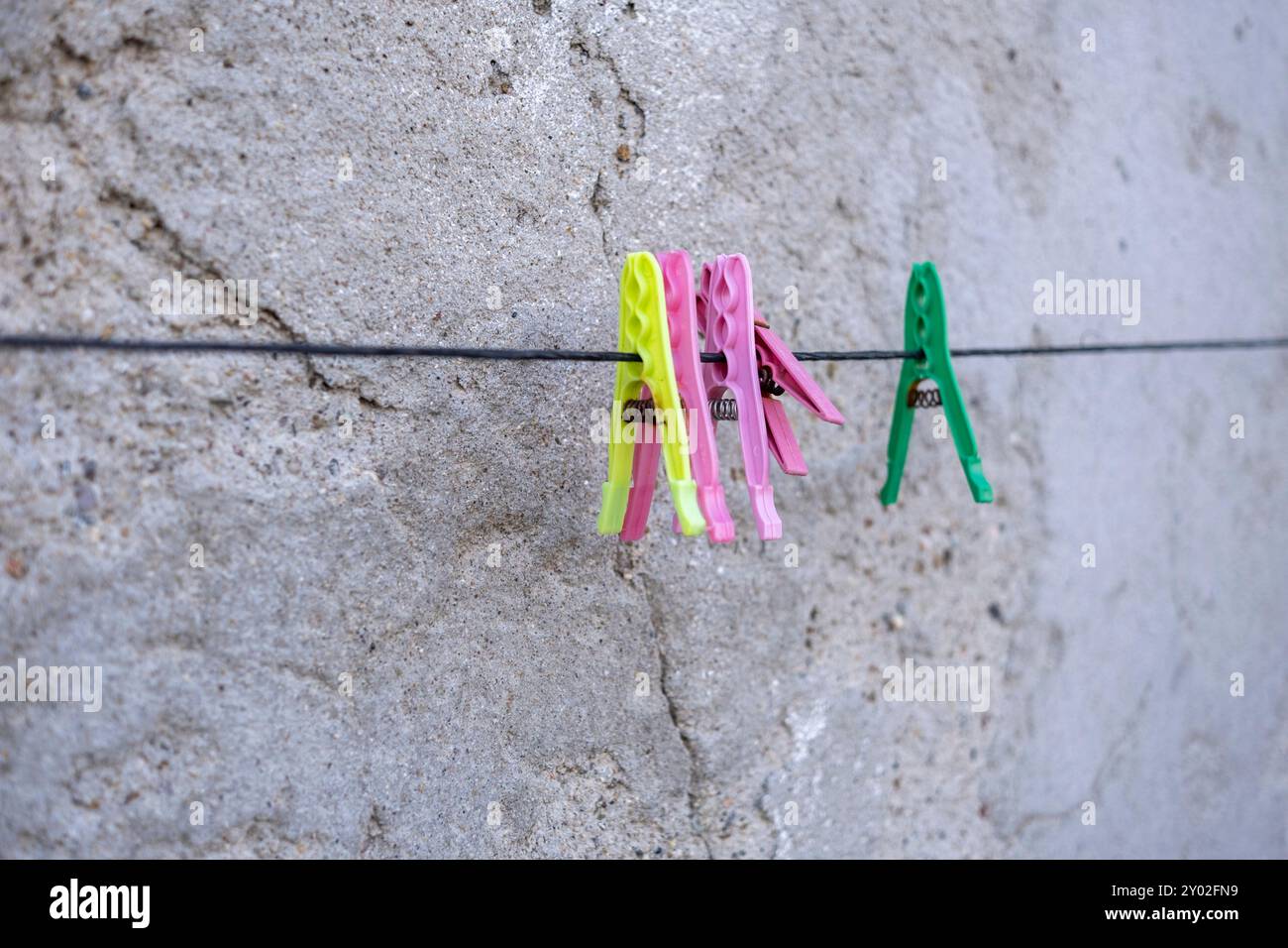 Plastic clothespin on line with grey wall Stock Photo