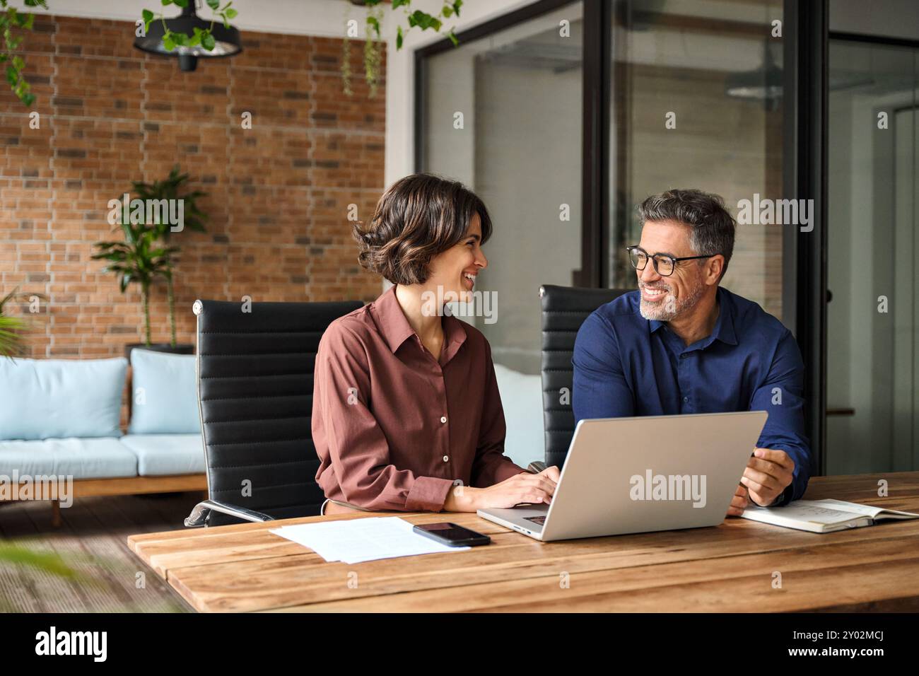 Two happy busy professional team business people working together on laptop. Stock Photo