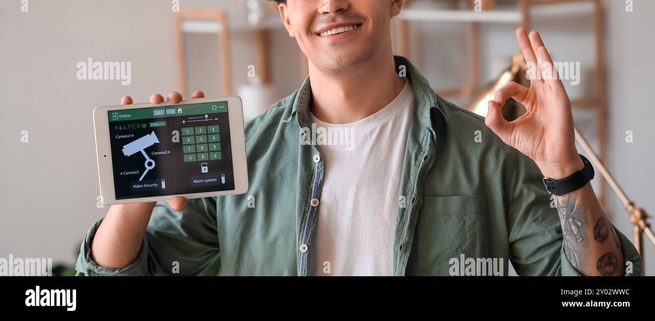 Young man holding tablet computer with smart home security system on screen Stock Photo