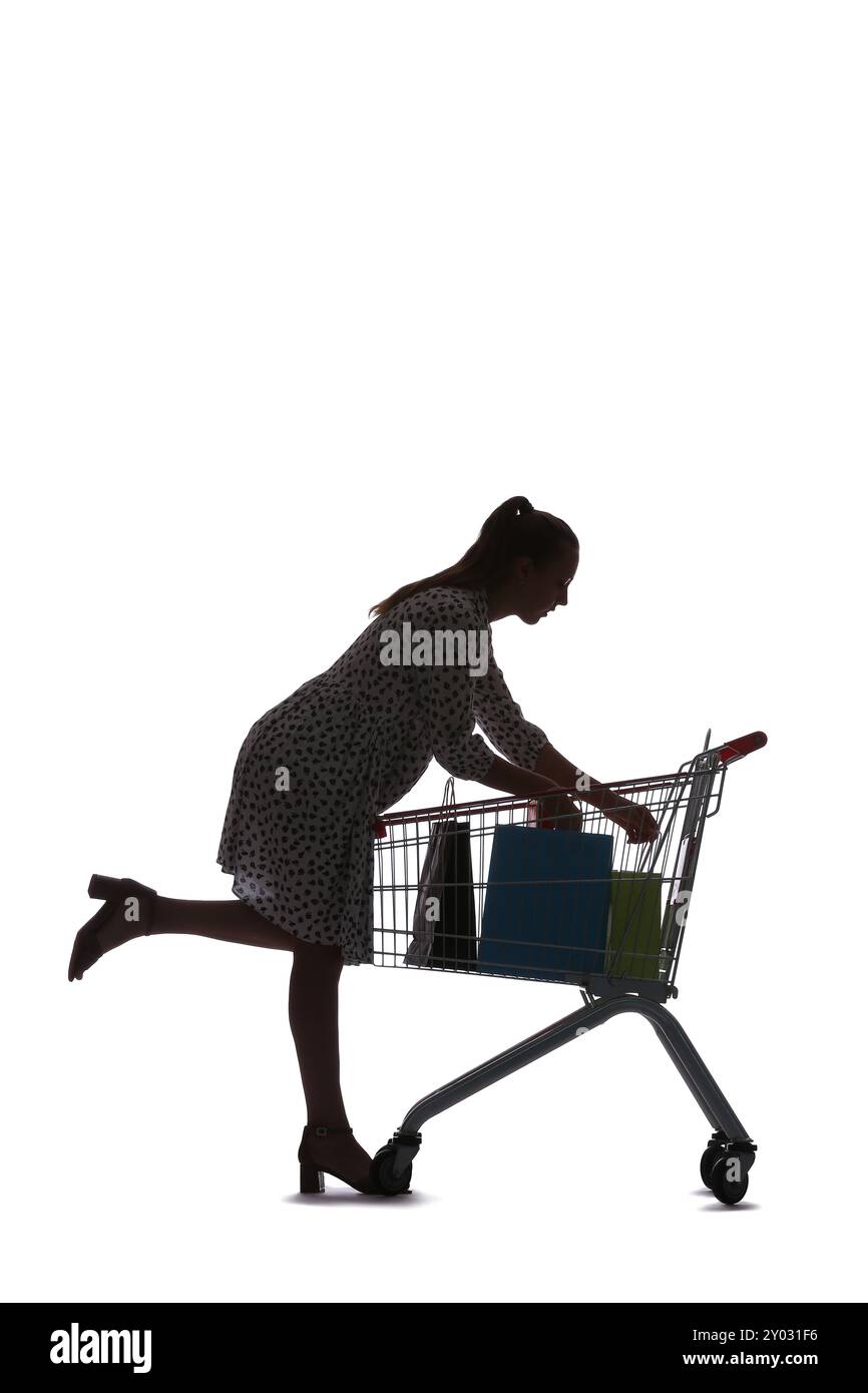 Silhouette of young woman with shopping cart on white background Stock Photo