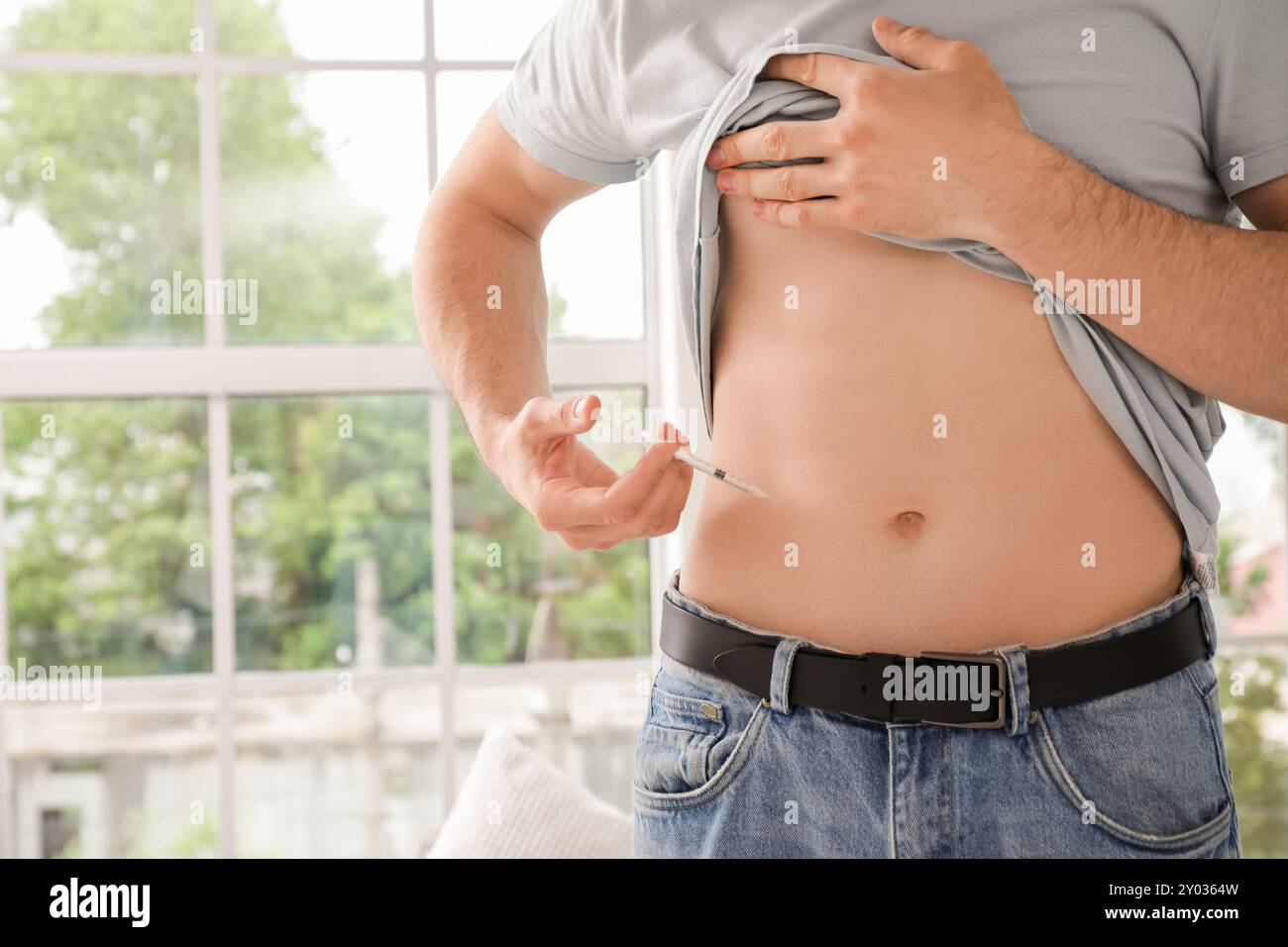 Diabetic young man giving himself insulin injection at home, closeup Stock Photo