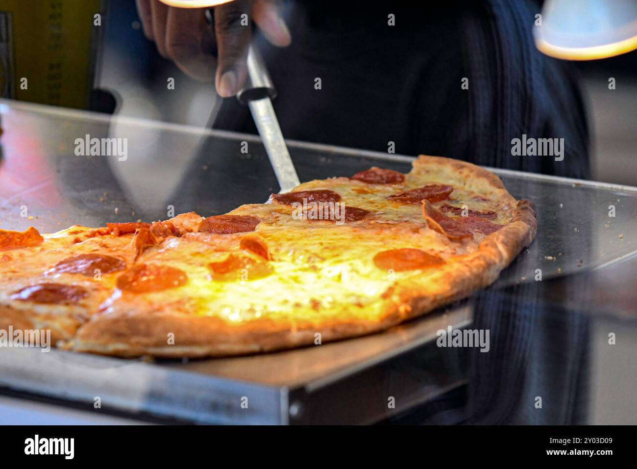 Close up of pepperoni pizza on a warming tray in a food truck as viewed through glass. Stock Photo