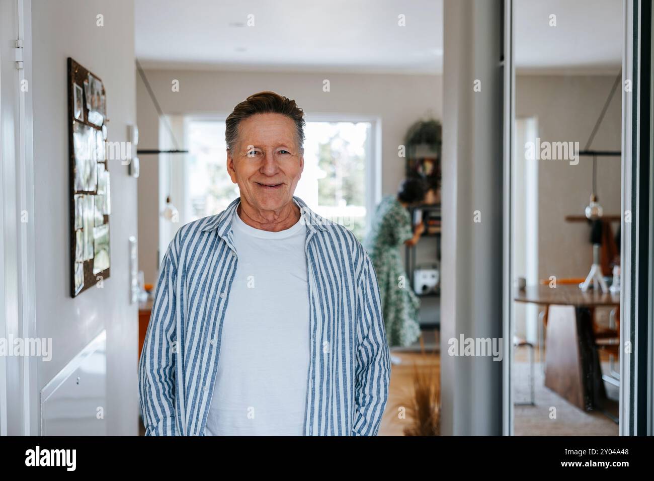 Portrait of smiling senior man in striped shirt at home Stock Photo