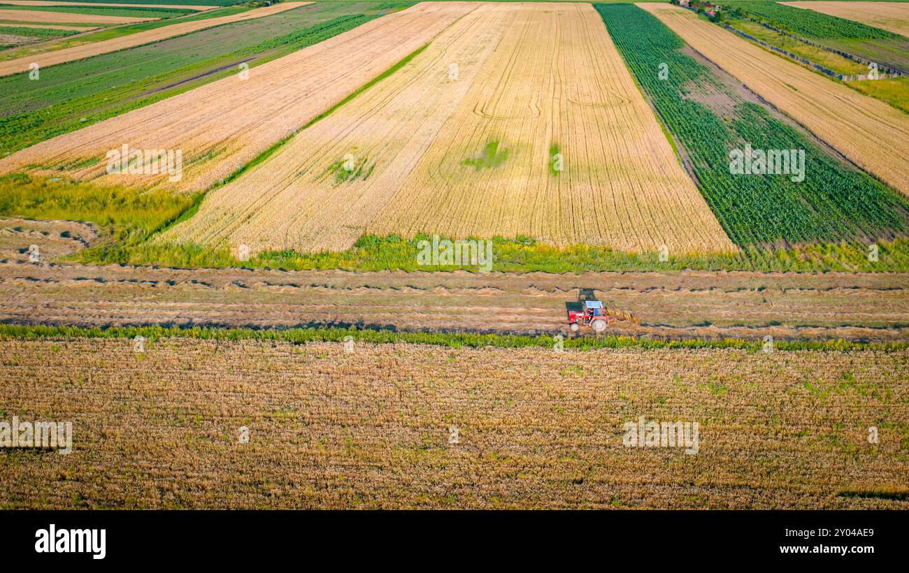 Tractor with attached mechanical rake is turning and gathering dry ...