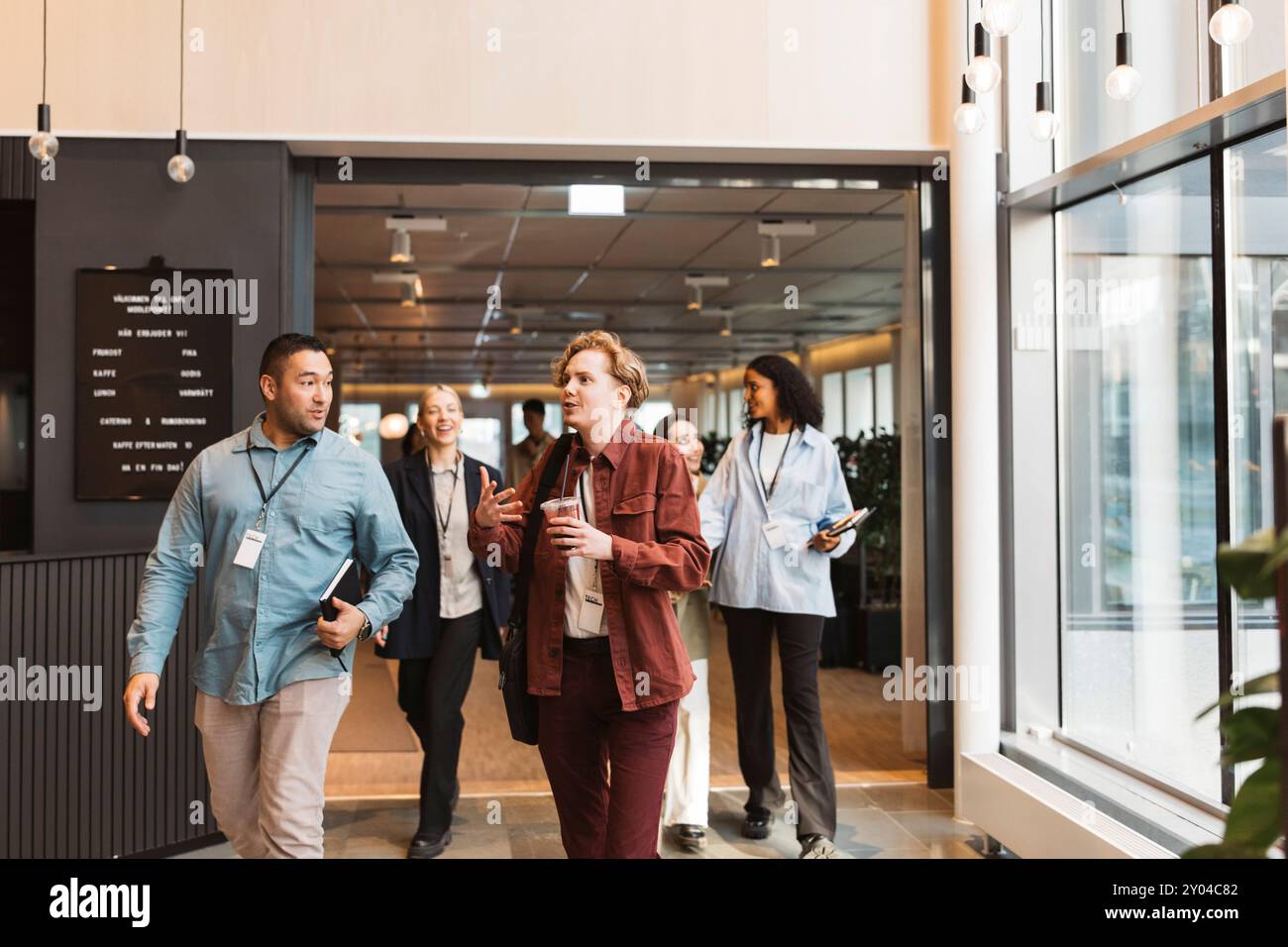 Male and female business delegates discussing while walking at convention center Stock Photo