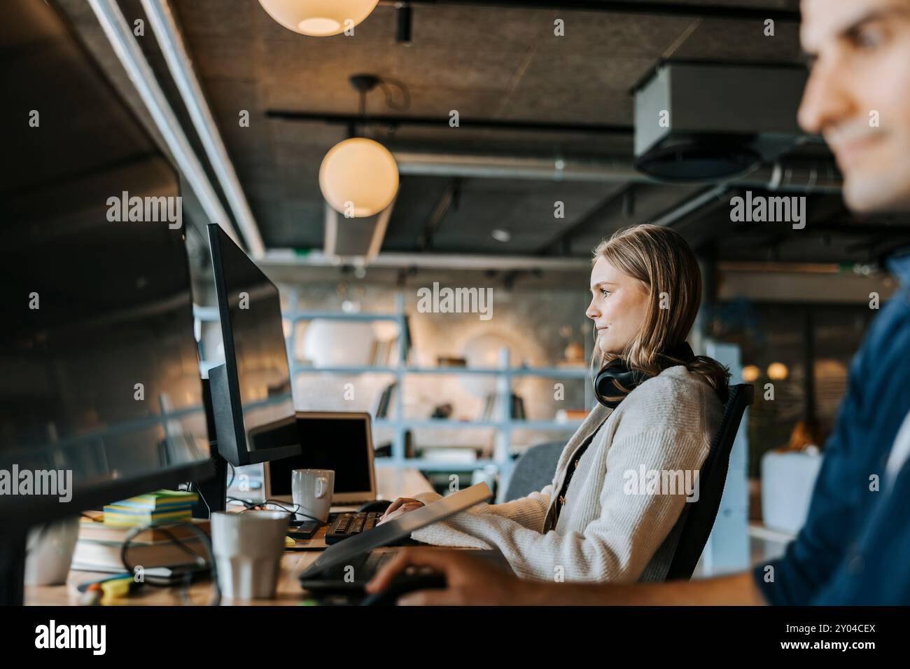Young female programmer doing coding while sitting at desk in office Stock Photo