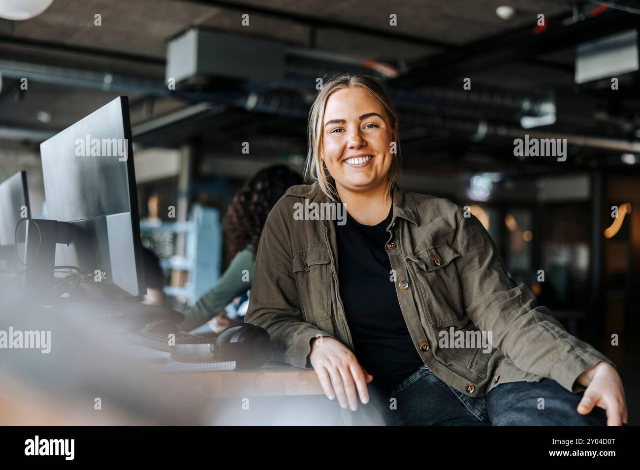 Portrait of happy female tech programmer leaning on desk sitting at ...