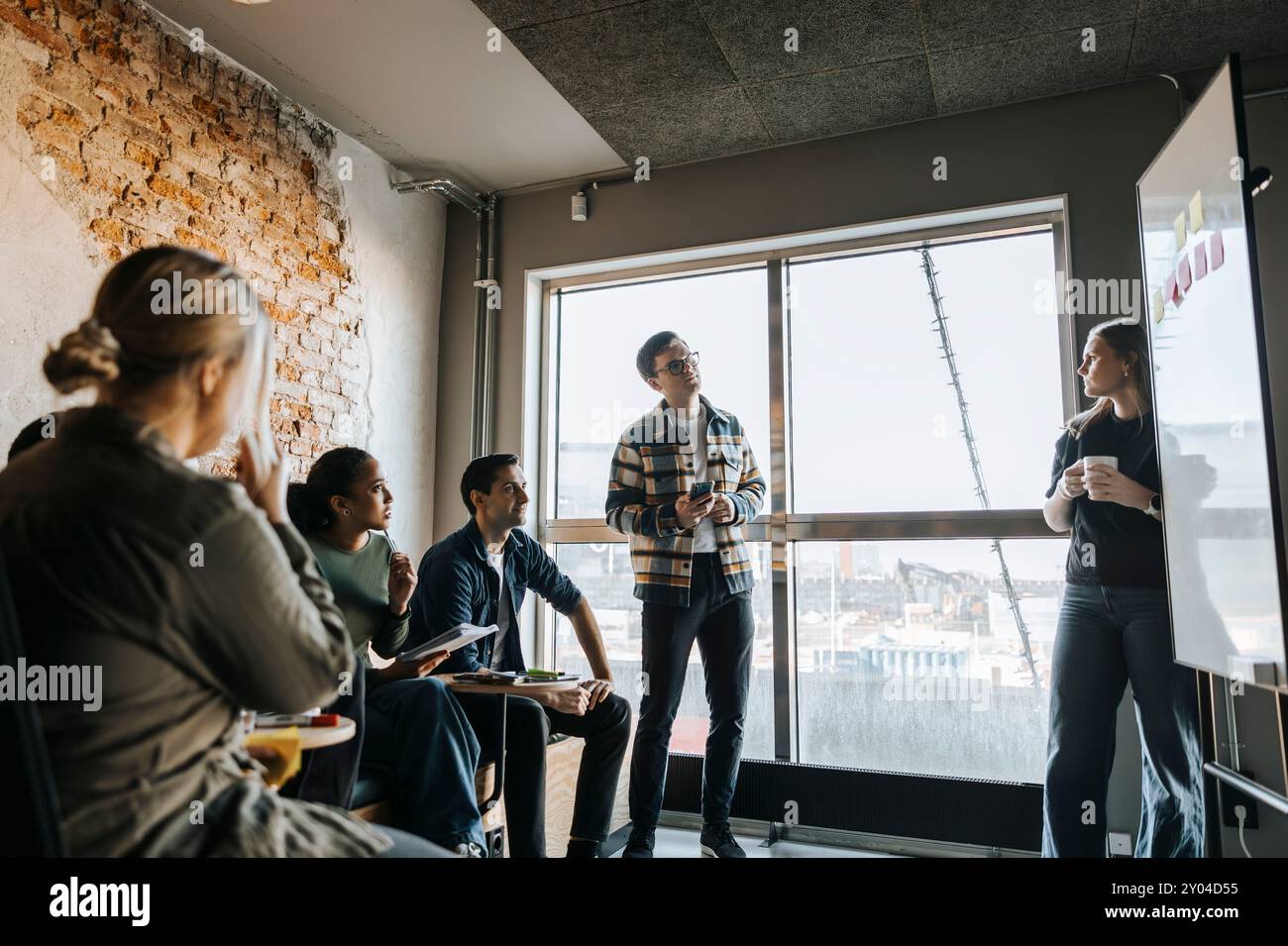 Young female programmer taking team meeting in tech startup office Stock Photo