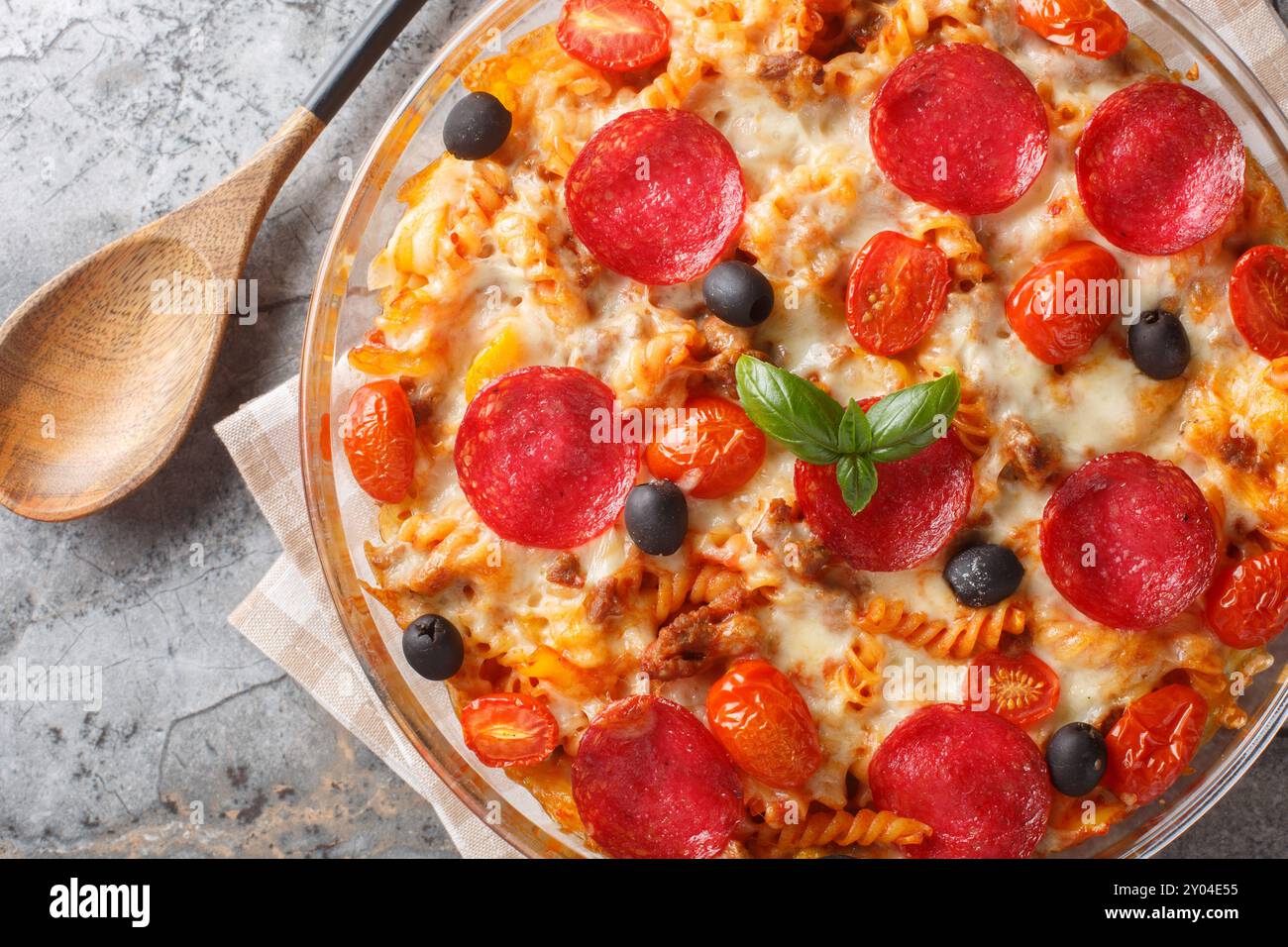 Pizza Casserole of tender pasta, browned beef meat, salami, olives, bell peppers and cheese smothered in marinara sauce closeup on the in a glass bowl Stock Photo