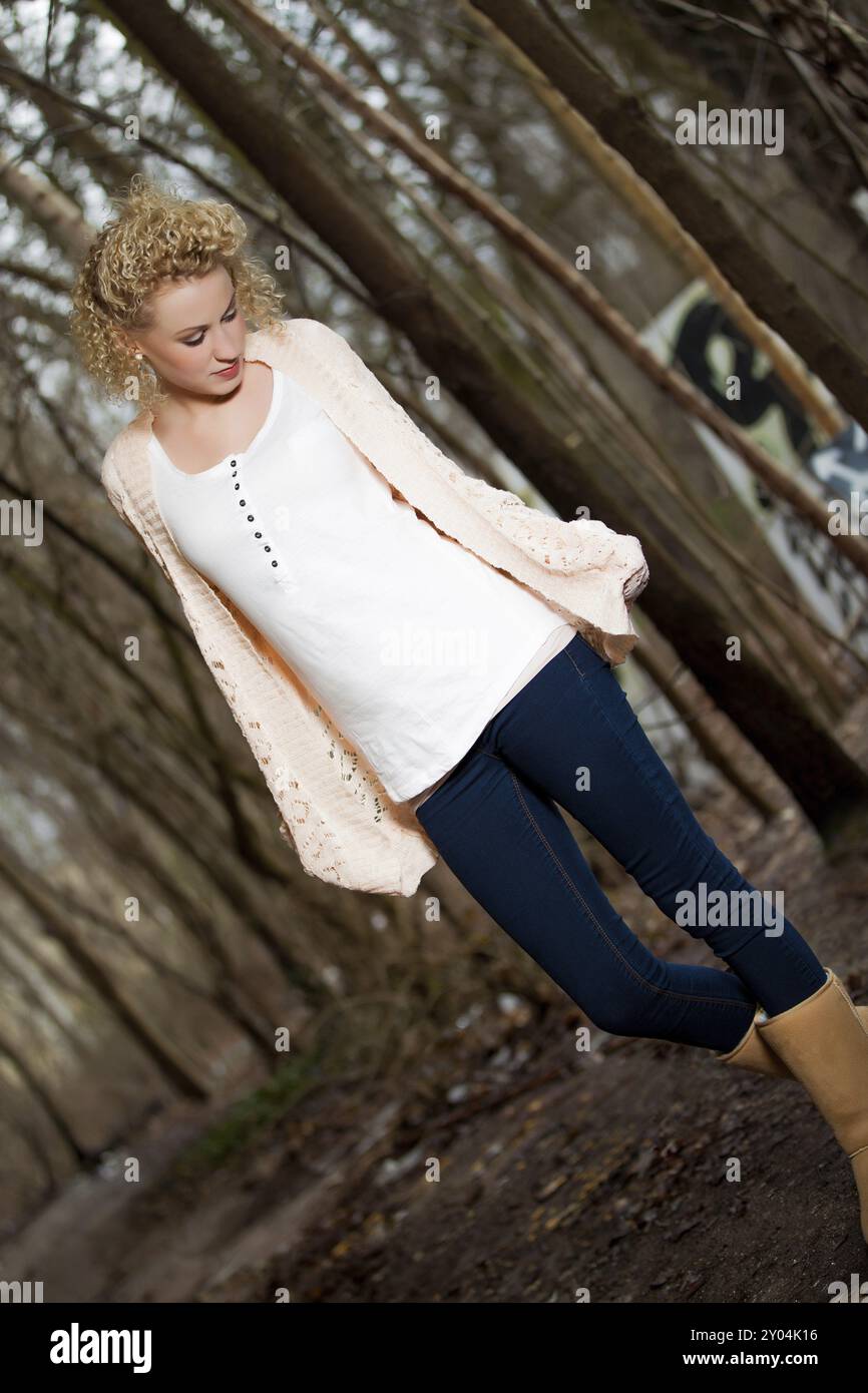 Young blonde woman with long curly hair in outdoor autumn environment Stock Photo