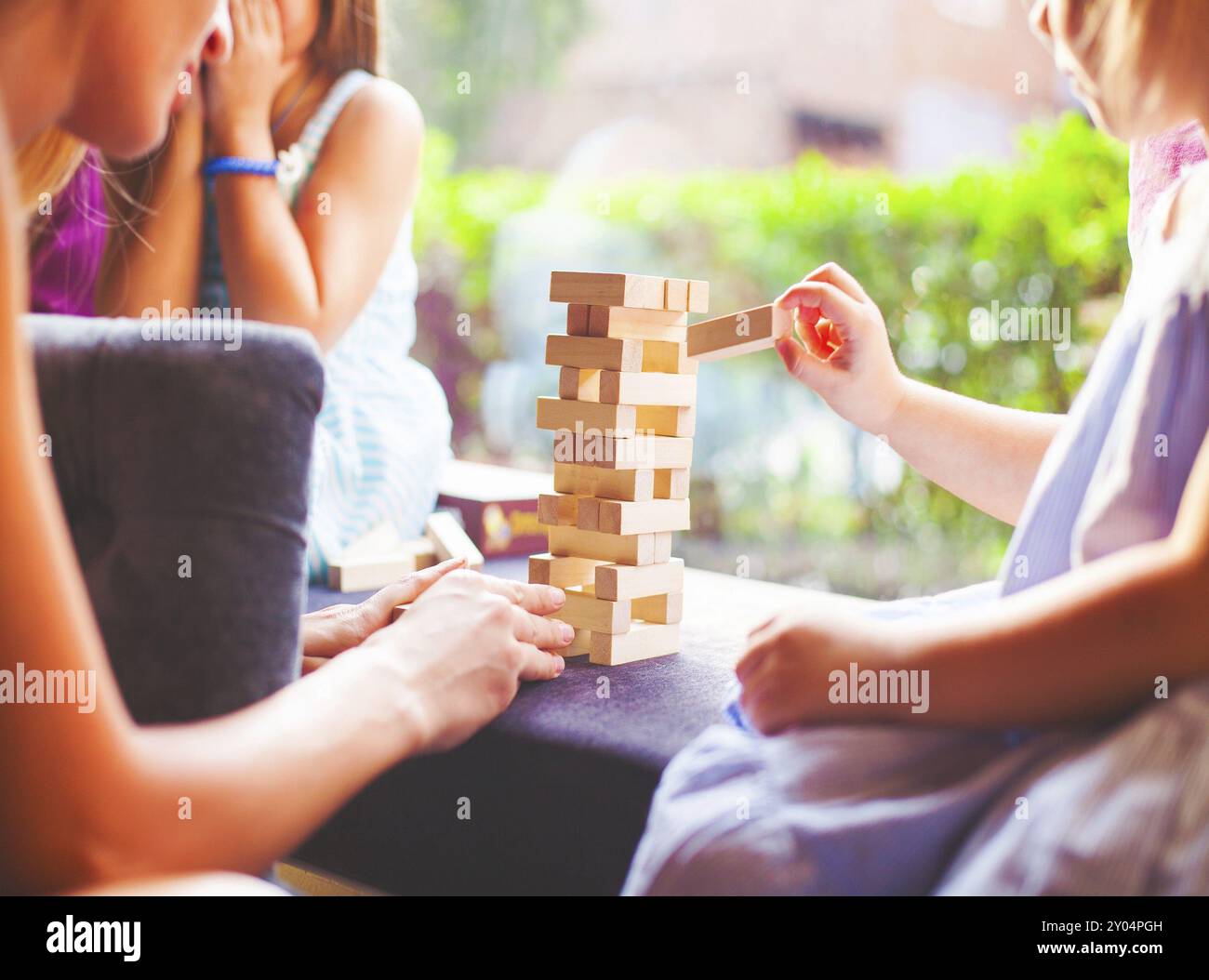 Happy mother with two children playing the wooden blocks tower at home ...