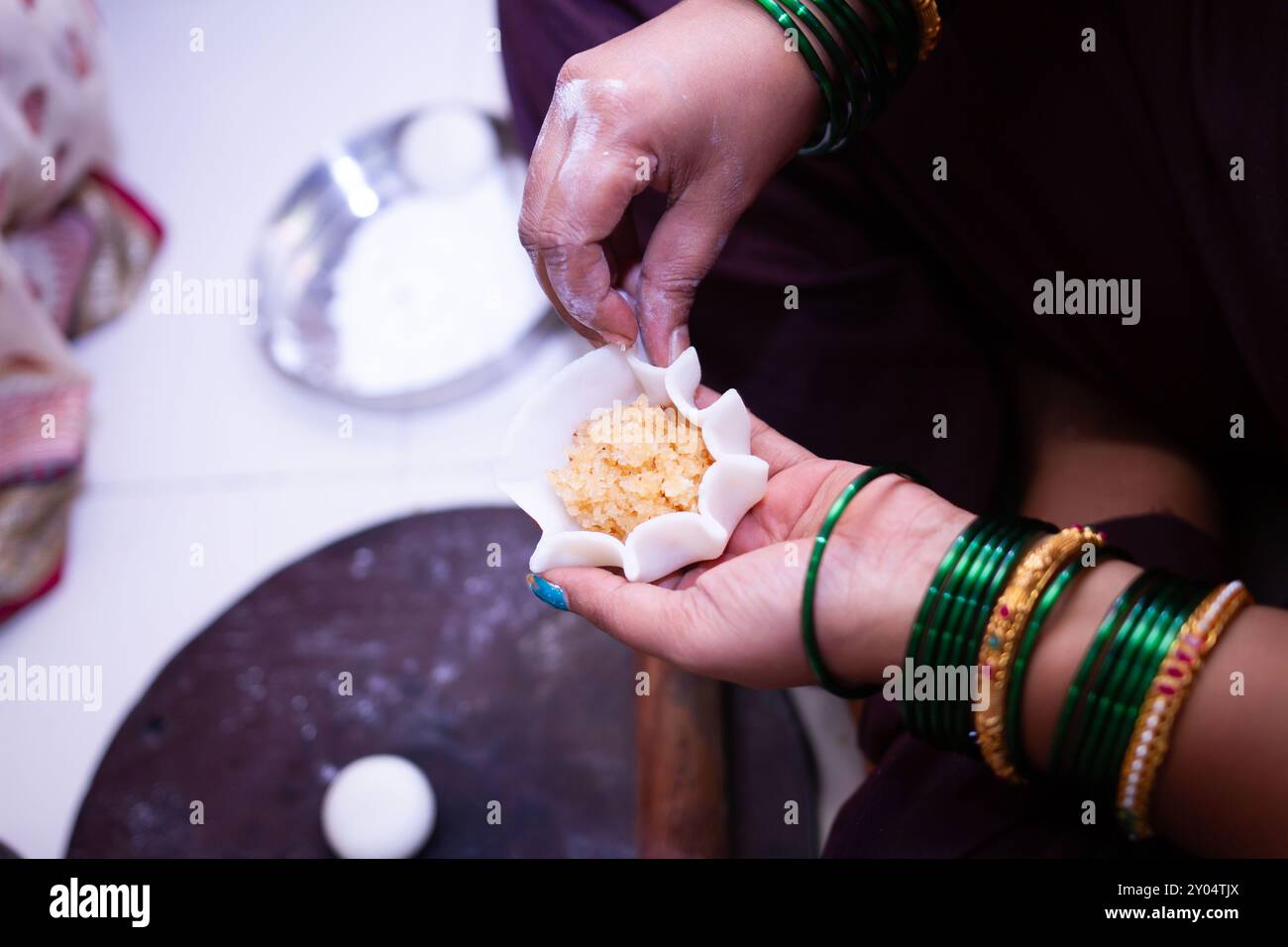 Woman making sweet rice modak stuffed with grated coconut and jaggery ...