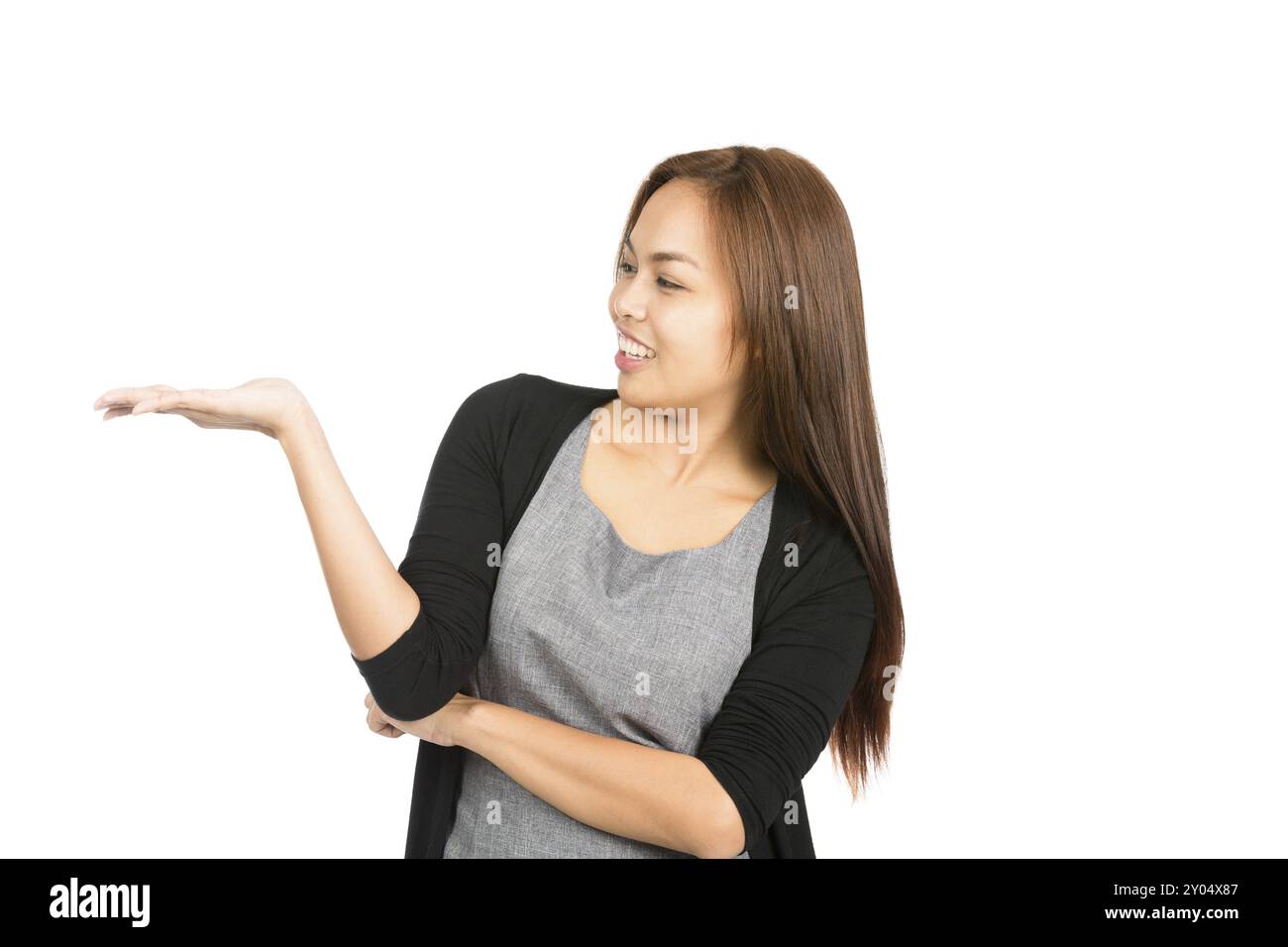 Profile of gorgeous smiling Asian woman in black sweater learning back with flat open palm holding imaginary inserted product looking at hand to side. Stock Photo