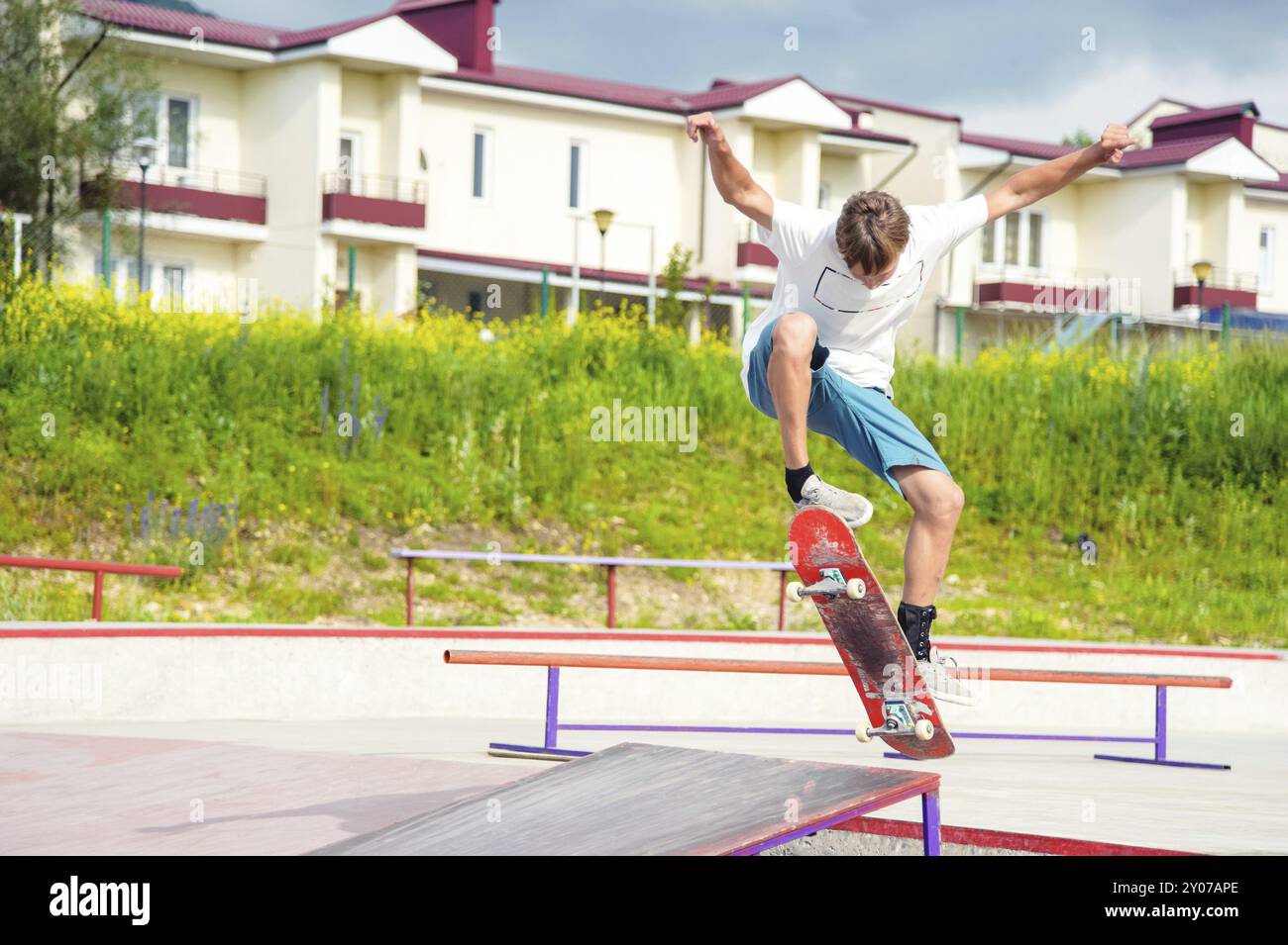 Boy skateboarder in a skate park doing an ollie trick on a skateboard against a sky and thunderclouds Stock Photo