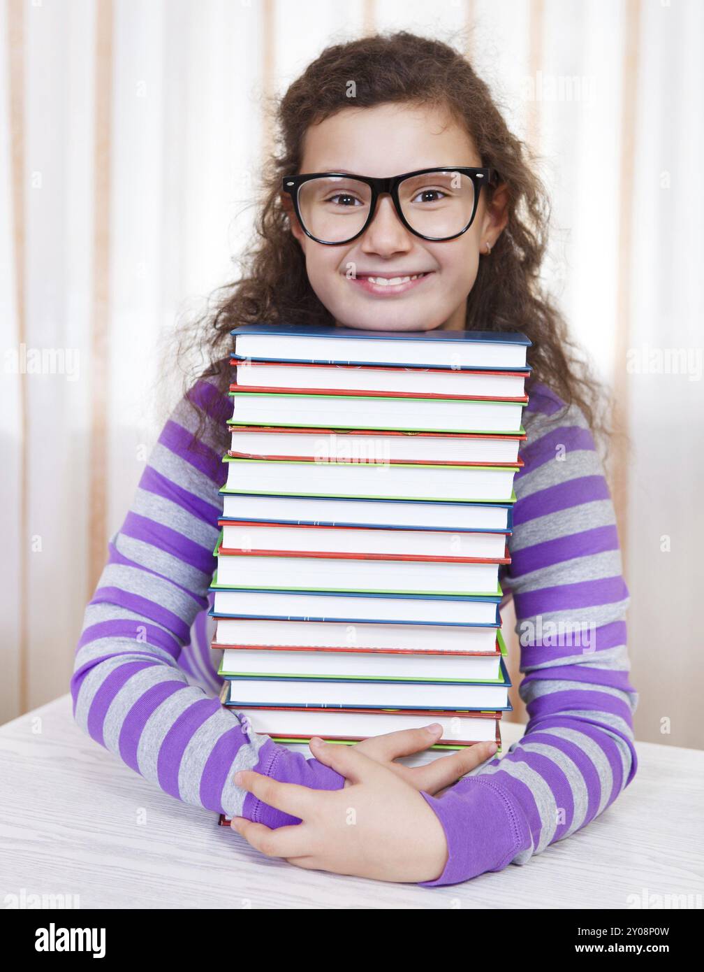 Little brunette smiling girl with piles of books Stock Photo - Alamy