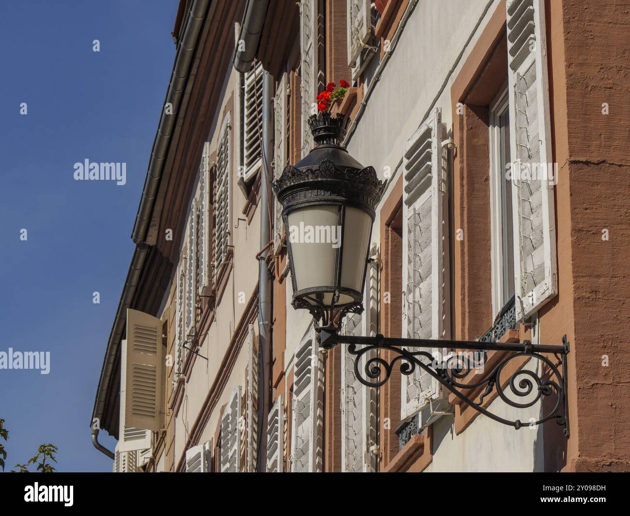 Historic half-timbered building with shaded shutters, decorated with flowers, a lamp stands out, Weissenburg, Alsace, France, Europe Stock Photo