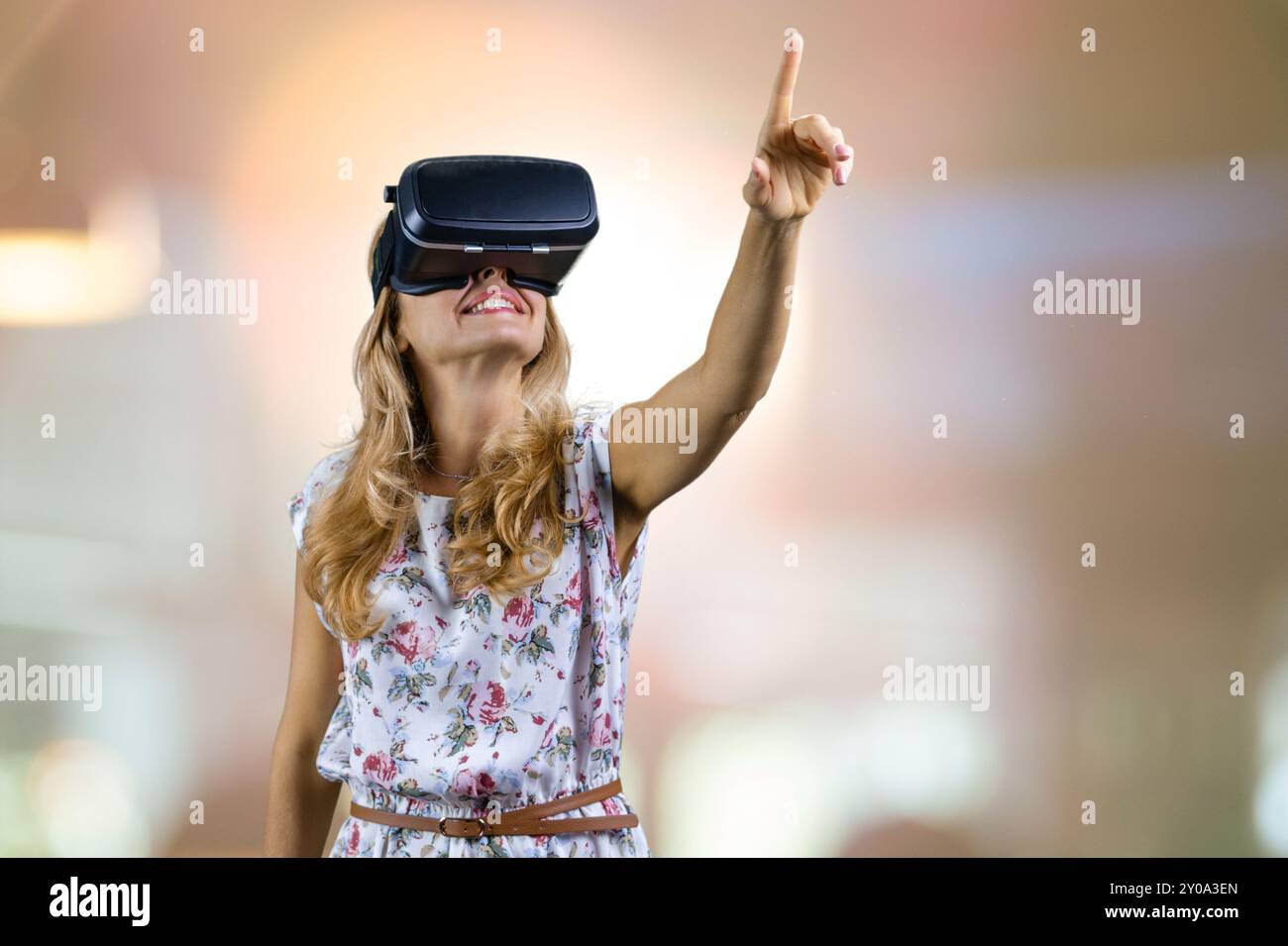 Happy amazed mature woman in virtual reality headset pointing up ...