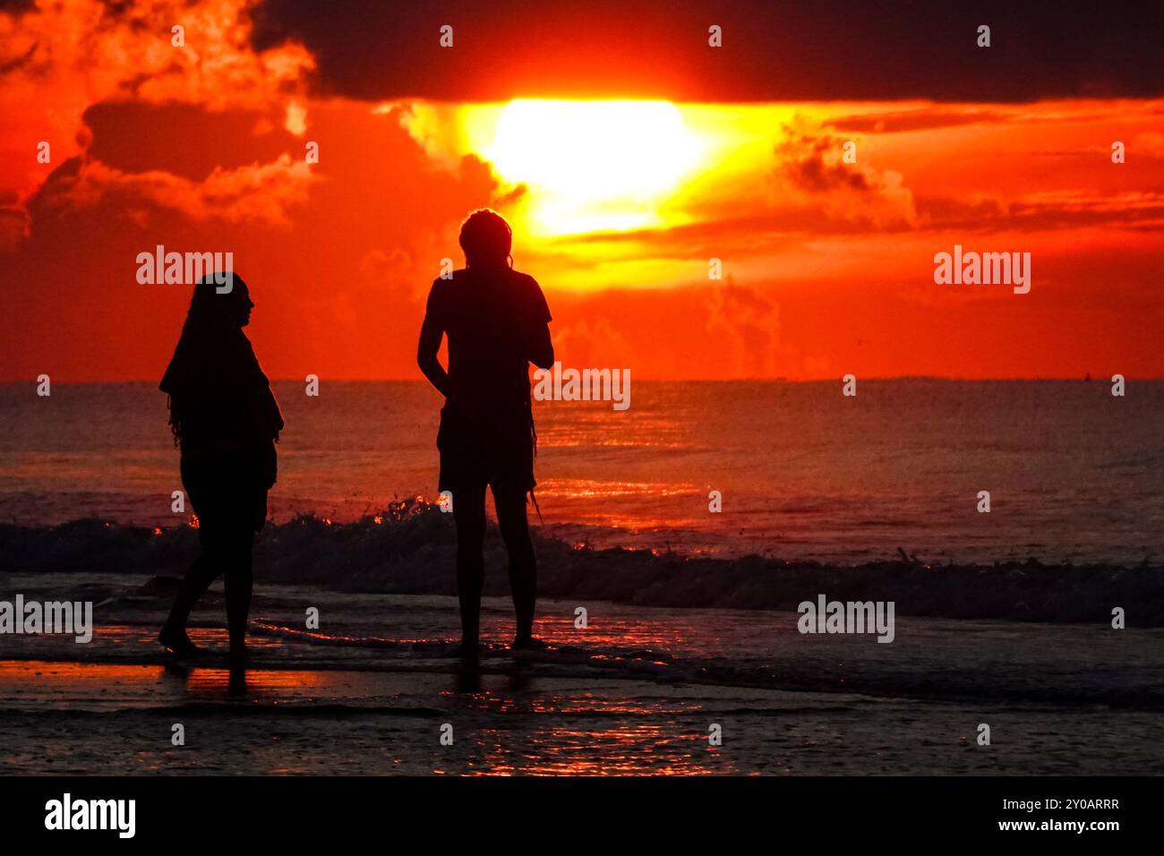 Isle Of Palms, United States. 31st Aug, 2024. A couple silhouetted by the sunrise watch as the sun breaks out under a storm cloud at the start of the Labor Day weekend on the beach, August 31, 2024 in Isle of Palms, South Carolina. Credit: Richard Ellis/Richard Ellis/Alamy Live News Stock Photo